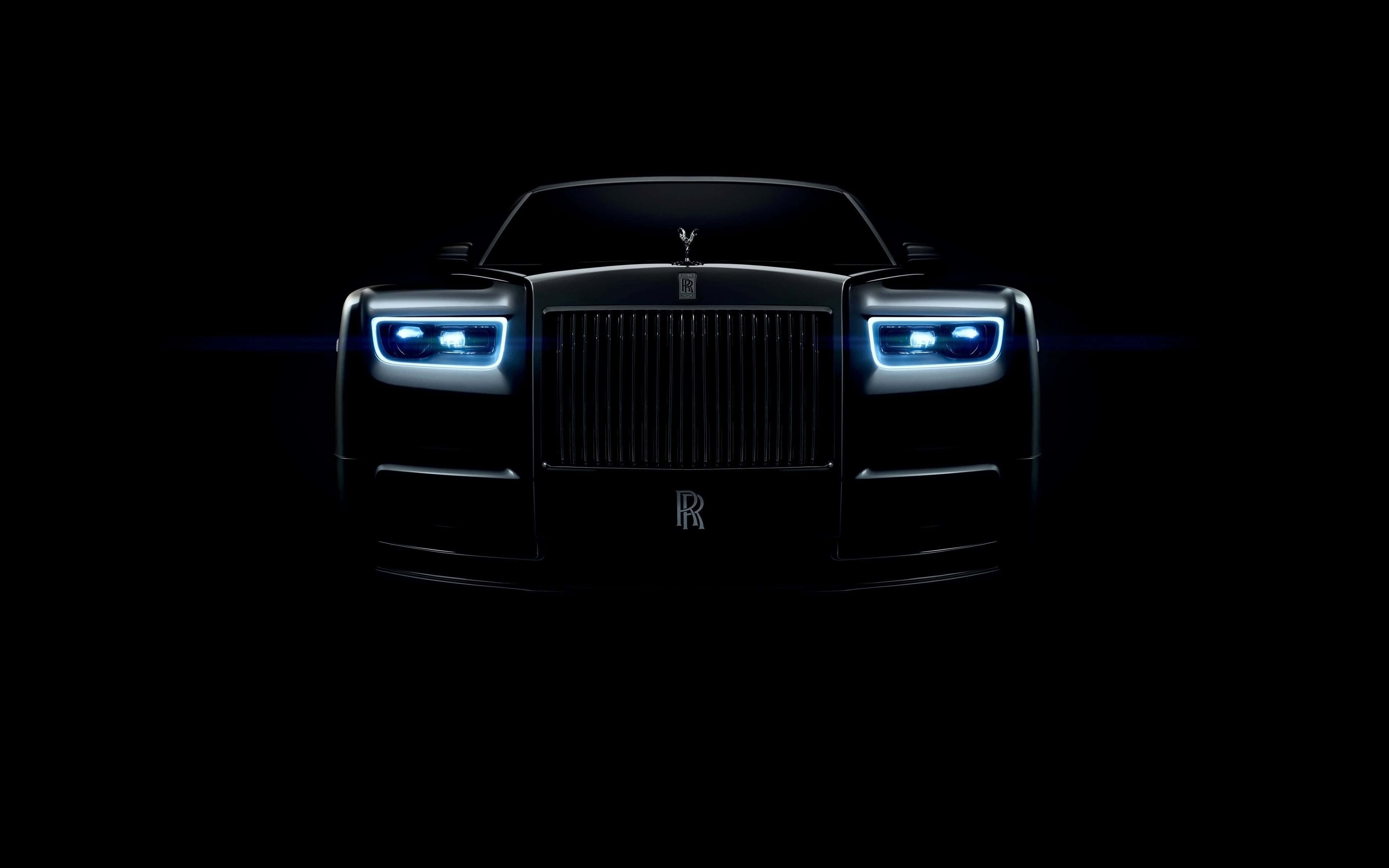Rolls Royce 桌布 壁紙 — 一輛勞斯萊斯幻影在漆黑背景下閃耀著明亮的藍色車頭燈。