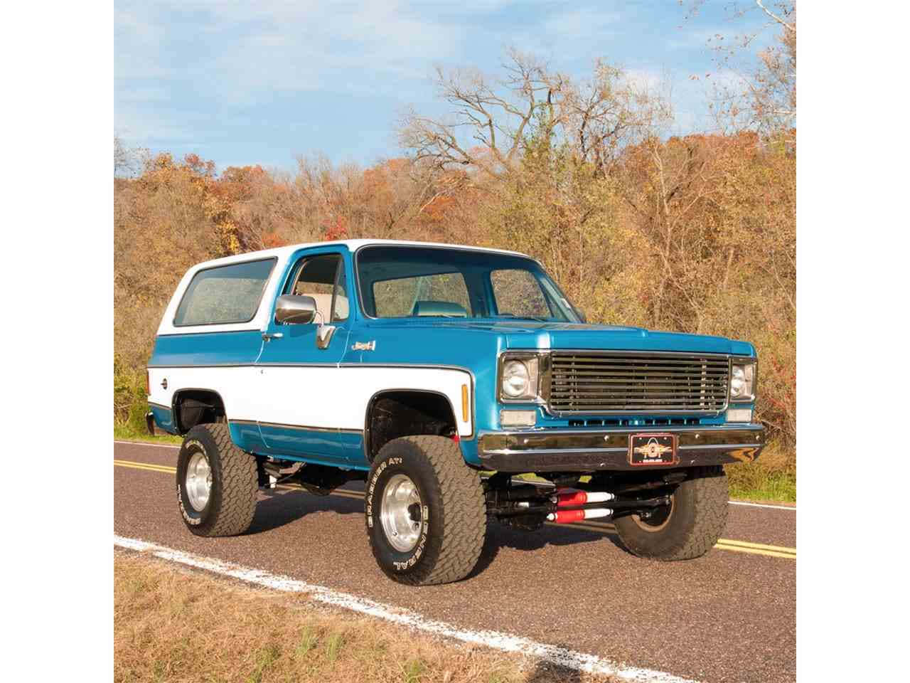 Gmc Jimmy 桌布 壁紙 — 一輛升高了的藍白色Jeep Cherokee在晴朗天空下行駛在鋪砌道路上，穿過秋天的樹林。