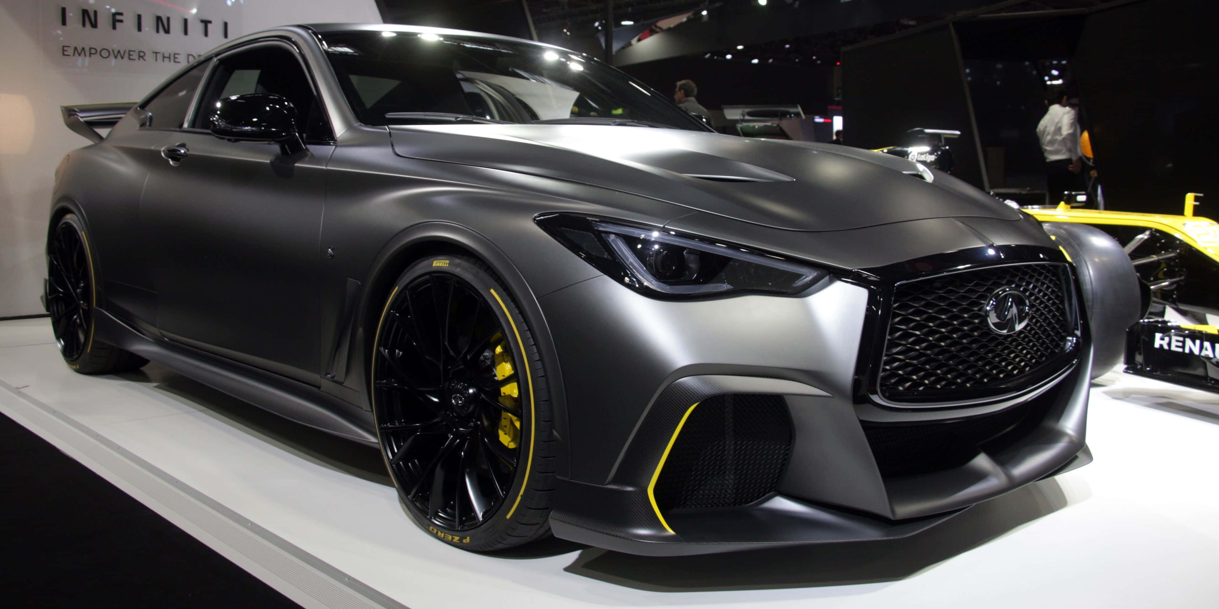 Infiniti Q60 桌布 壁紙 — 一輛啞光灰色的Infiniti跑車，車輪和飾條上帶有醒目的黃色點綴，在車展的白色平台上展示。