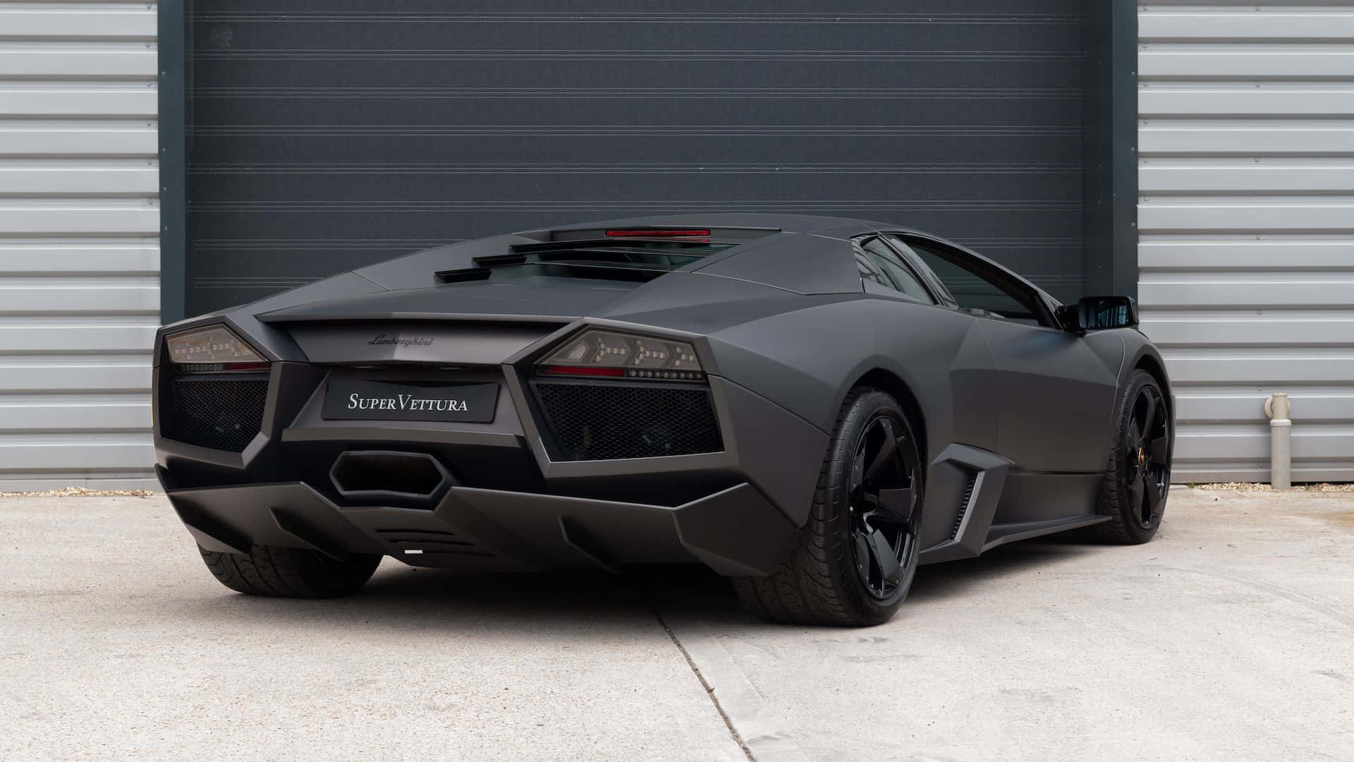 Lamborghini Reventón 桌布 壁紙 — 一輛啞光黑色的林寶堅尼 Reventón SuperVettura 停在工業車庫門前，地面是混凝土。