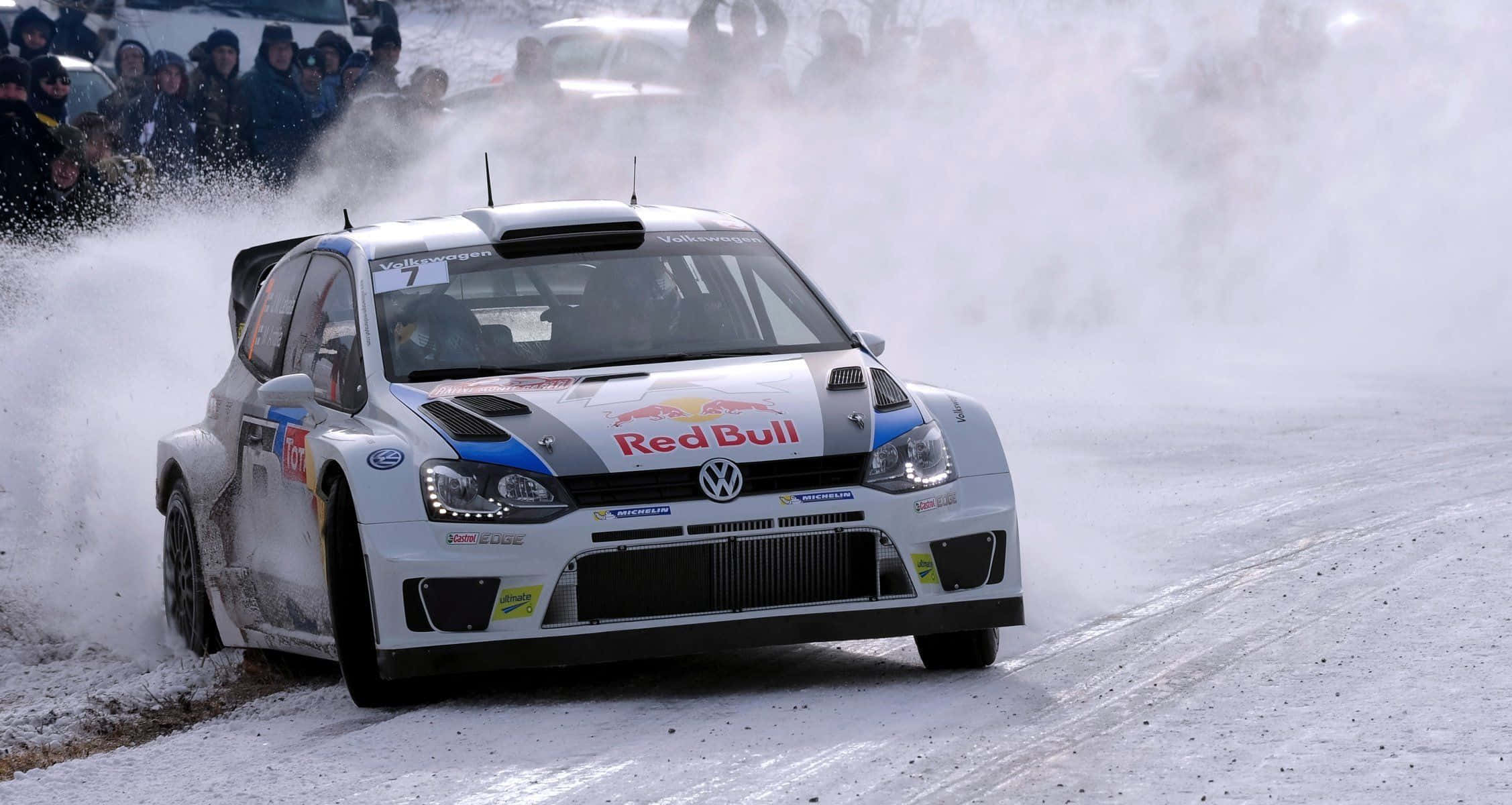 Ice Racing 桌布 壁紙 — 一輛帶有Red Bull品牌標誌的白色福士偉根拉力賽車在雪地彎道疾馳，激起大量雪和冰花。