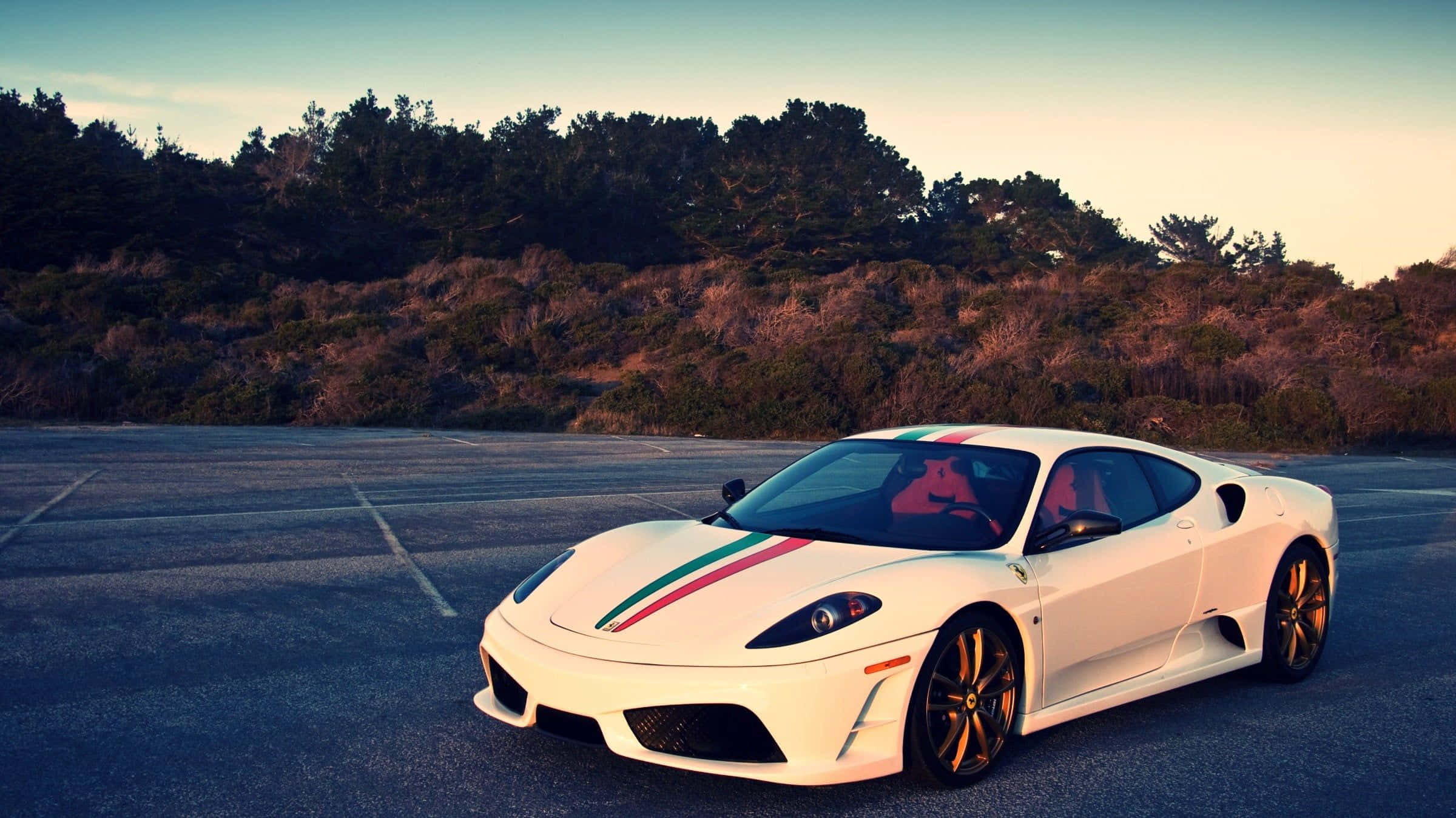 Ferrari F430 桌布 壁紙 — 一輛帶有意大利國旗條紋的白色法拉利跑車，在日落時分停泊在瀝青停車場，背景有樹木。