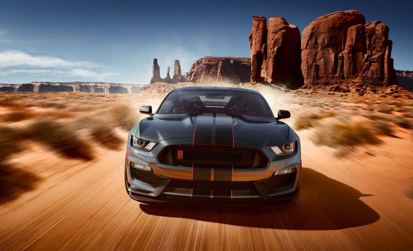 Ford Mustang Shelby Gt350 桌布 壁紙 — 一輛帶有橙色條紋的黑色福特野馬在沙漠景觀中疾馳，在紅色岩層附近揚起灰塵。