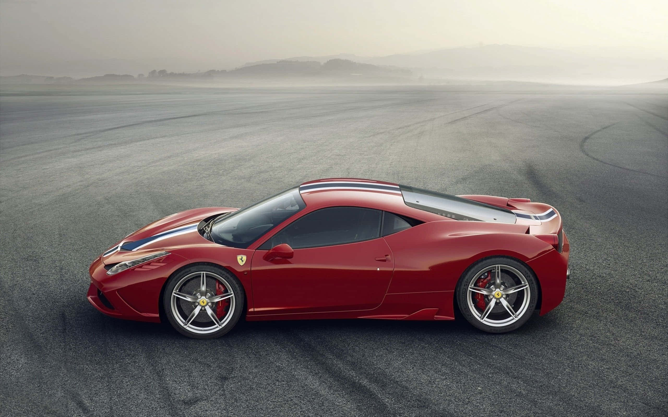 Ferrari 458 Speciale 桌布 壁紙 — 一輛帶有藍白條紋的時尚紅色法拉利跑車停泊在霧氣瀰漫的瀝青賽道上，遠處有山丘。
