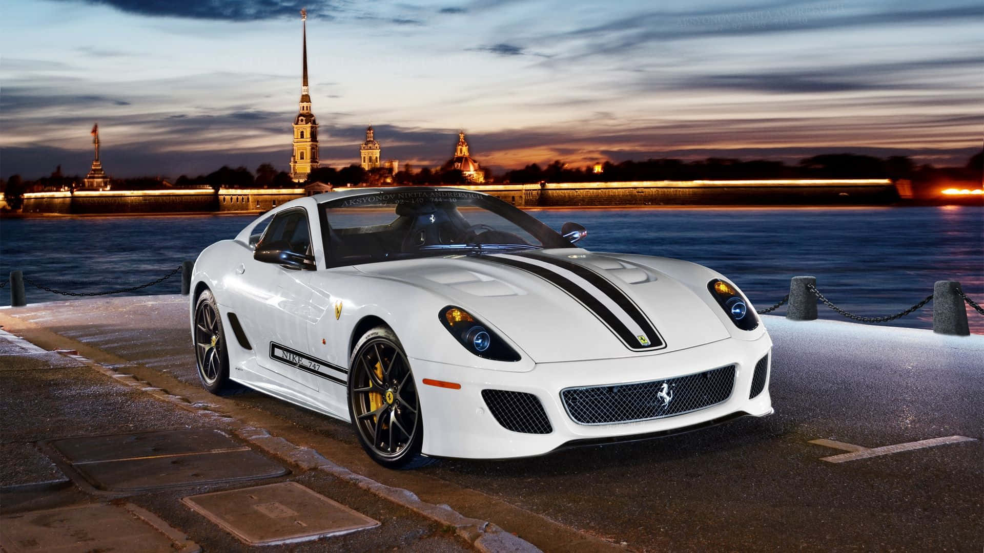 Ferrari 599 Gtb Fiorano 桌布 壁紙 — 一輛帶有黑色條紋的白色法拉利跑車停在海濱碼頭上，夕陽西下，歷史建築在背景中閃耀。