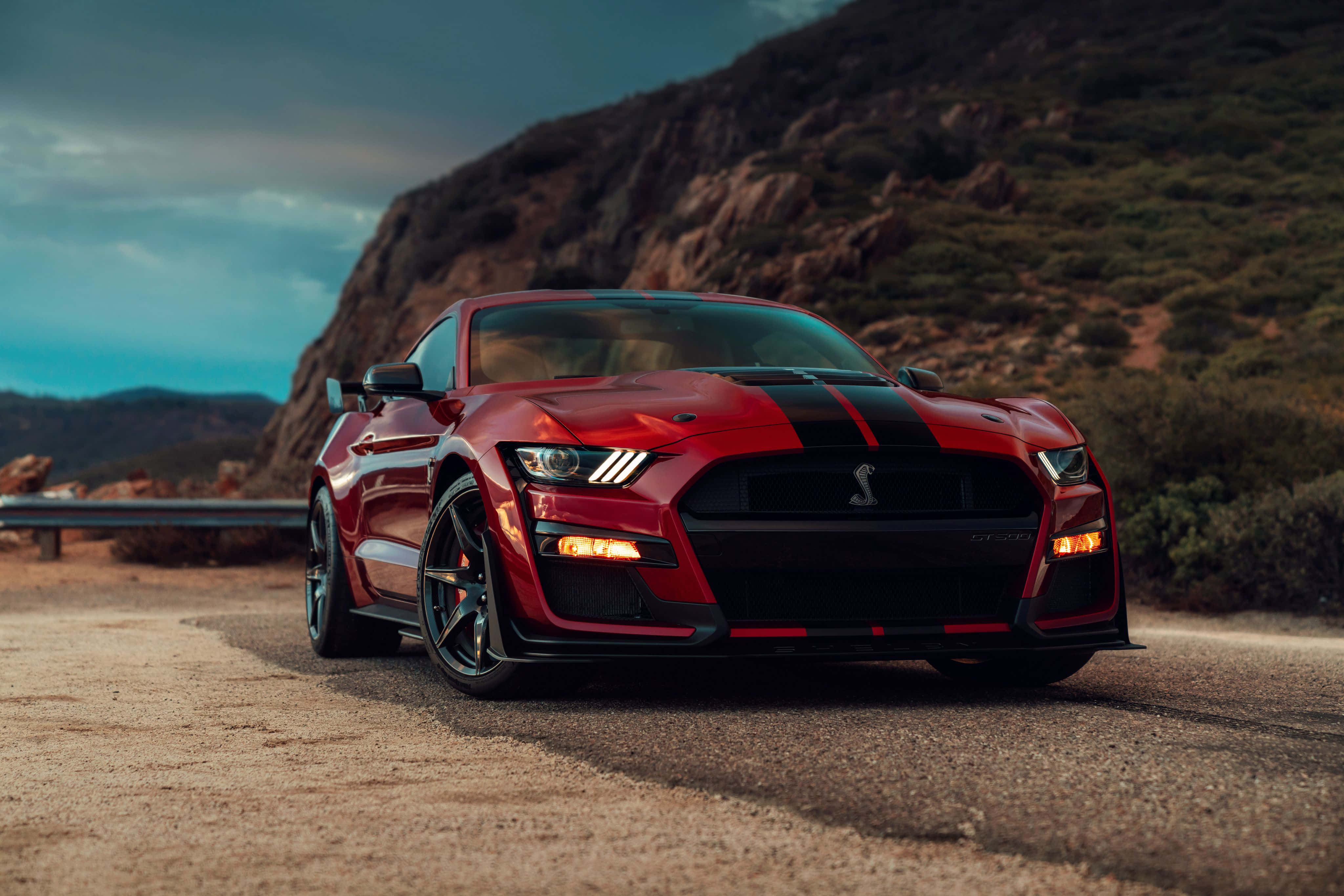 Ford Mustang Shelby Gt350 桌布 壁紙 — 一輛帶有黑色條紋的紅色Shelby Mustang GT500在黃昏時停泊在蜿蜒的山路上。