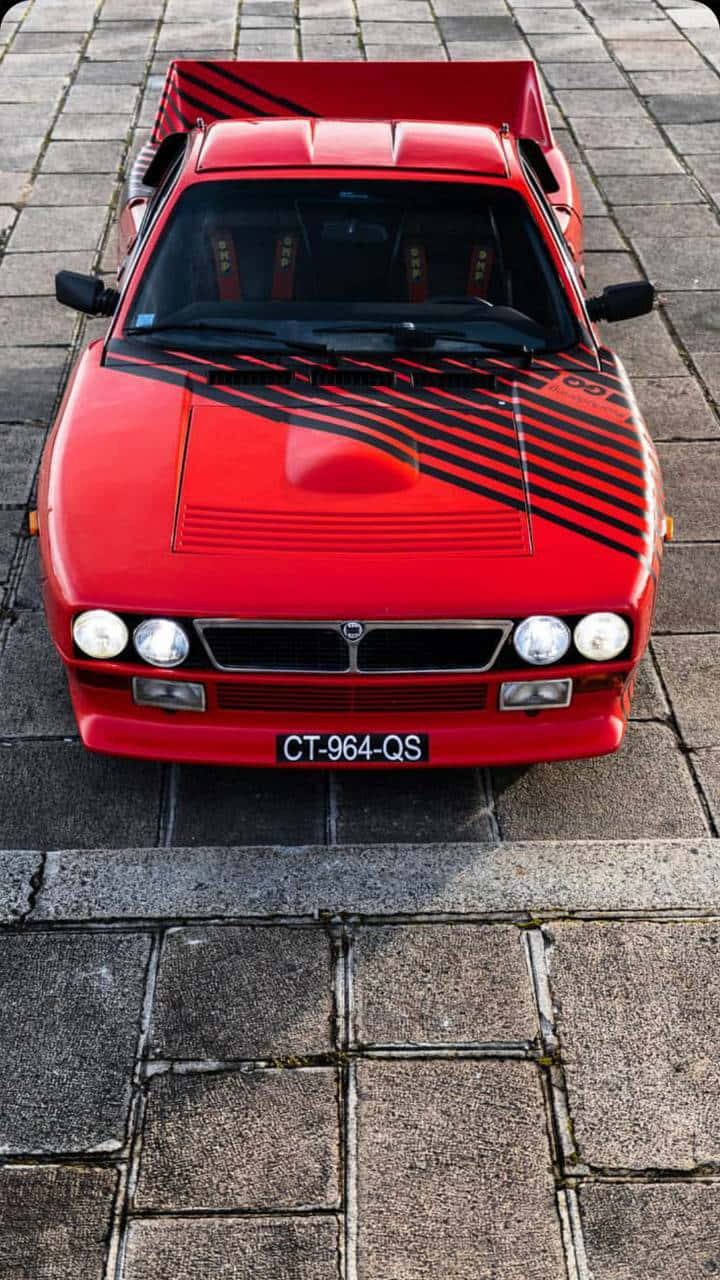 Lancia 桌布 壁紙 — 一輛帶有黑色賽車條紋的鮮紅色復古皮卡車停在石鋪地面上。