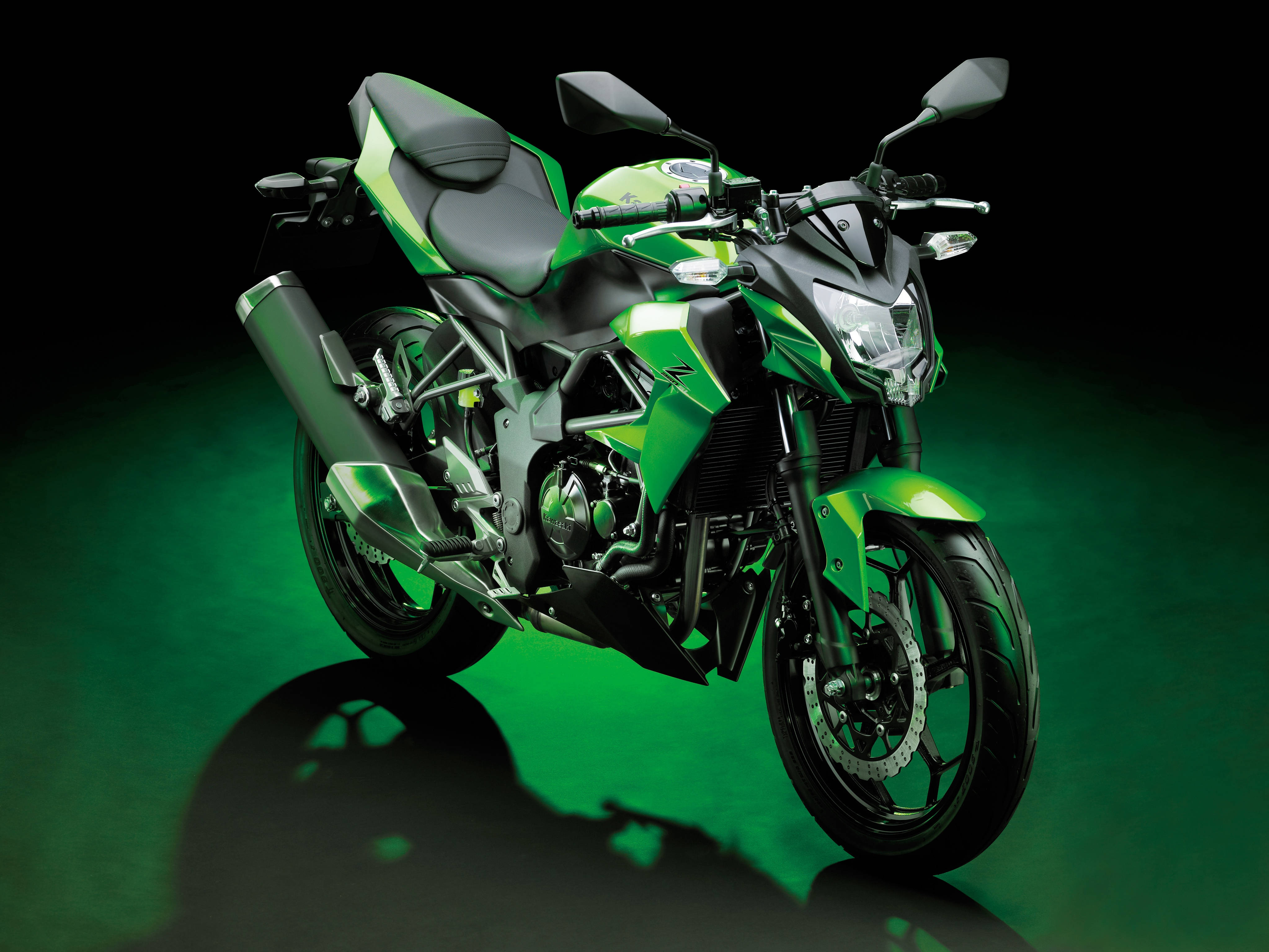 Kawasaki Desktop 桌布 壁紙 — 一輛帶有黑色點綴的時尚綠色運動電單車，在黑暗背景和發光的綠色地板反射下，被戲劇性地照亮。