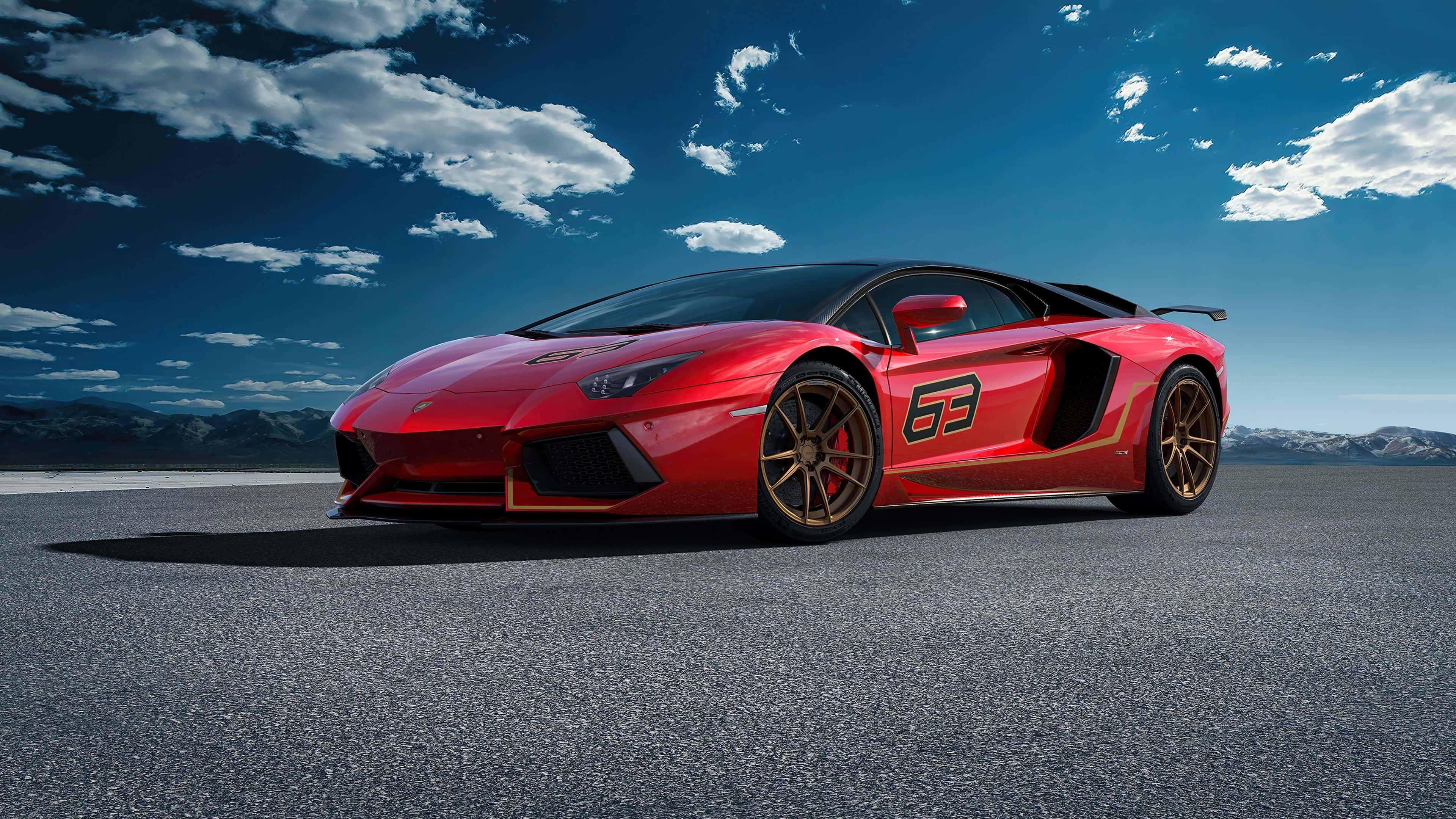 林寶堅尼 4K 桌布 壁紙 — 一輛引人注目的紅色林寶堅尼 Aventador SVJ，帶有金色飾邊和賽車號碼「63」，停在沙漠瀝青路上，背景是戲劇性的藍天和散落的雲朵。