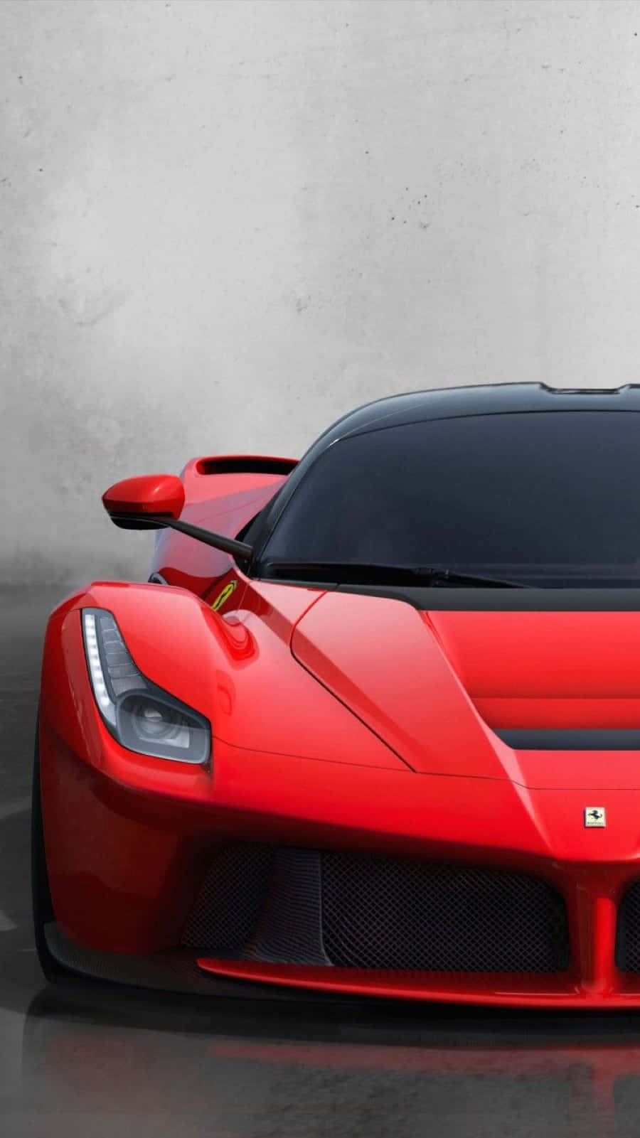 Ferrari Laferrari 桌布 壁紙 — 一輛引人注目的紅色法拉利LaFerrari跑車，擁有流線型空氣動力學設計和發光的車頭燈，以極簡的灰色混凝土背景為襯托。