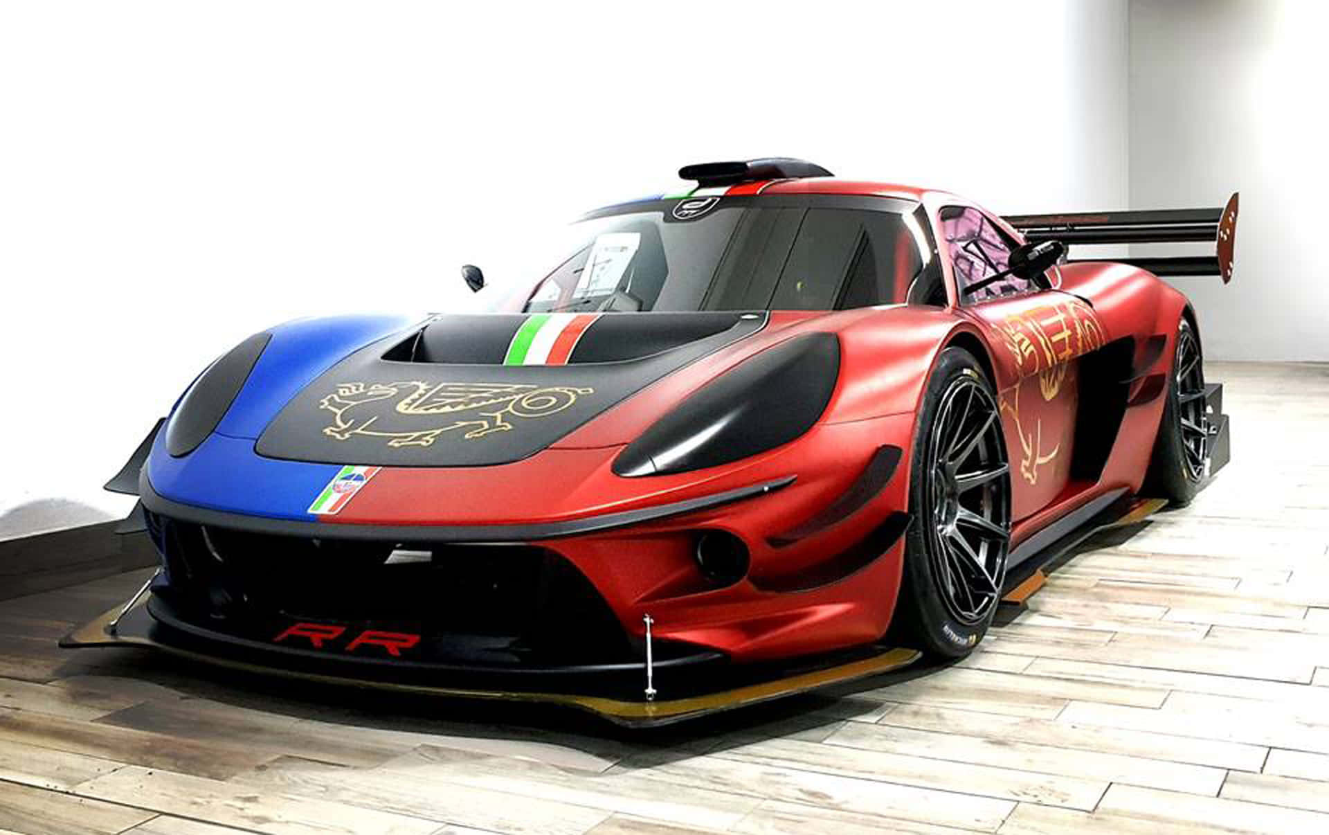 Car Racing 桌布 壁紙 — 一輛引人注目的紅藍色法拉利賽車，帶有金色龍形貼花和意大利國旗條紋，停放在極簡主義工作室的木地板上。