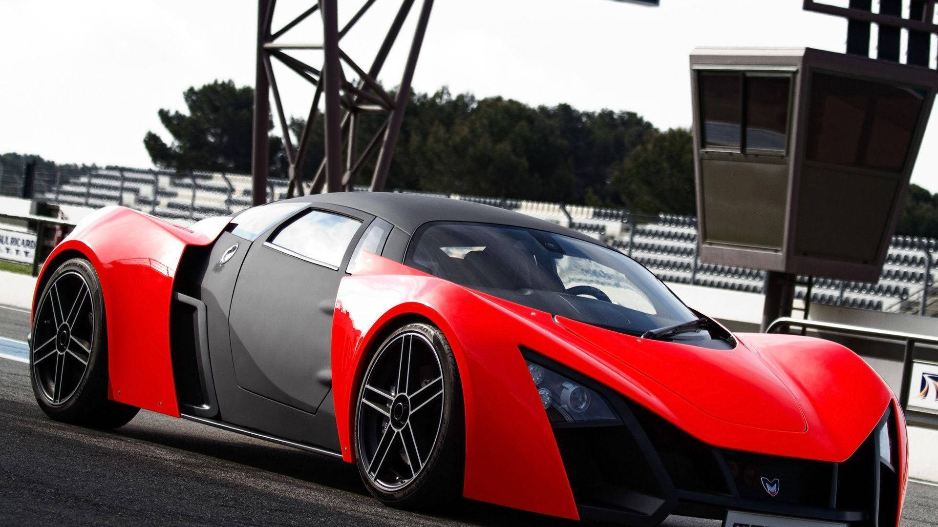 Sports Car 桌布 壁紙 — 一輛引人注目的紅黑配色跑車，採用時尚的空氣動力學設計，停在賽道上，背景是看台。