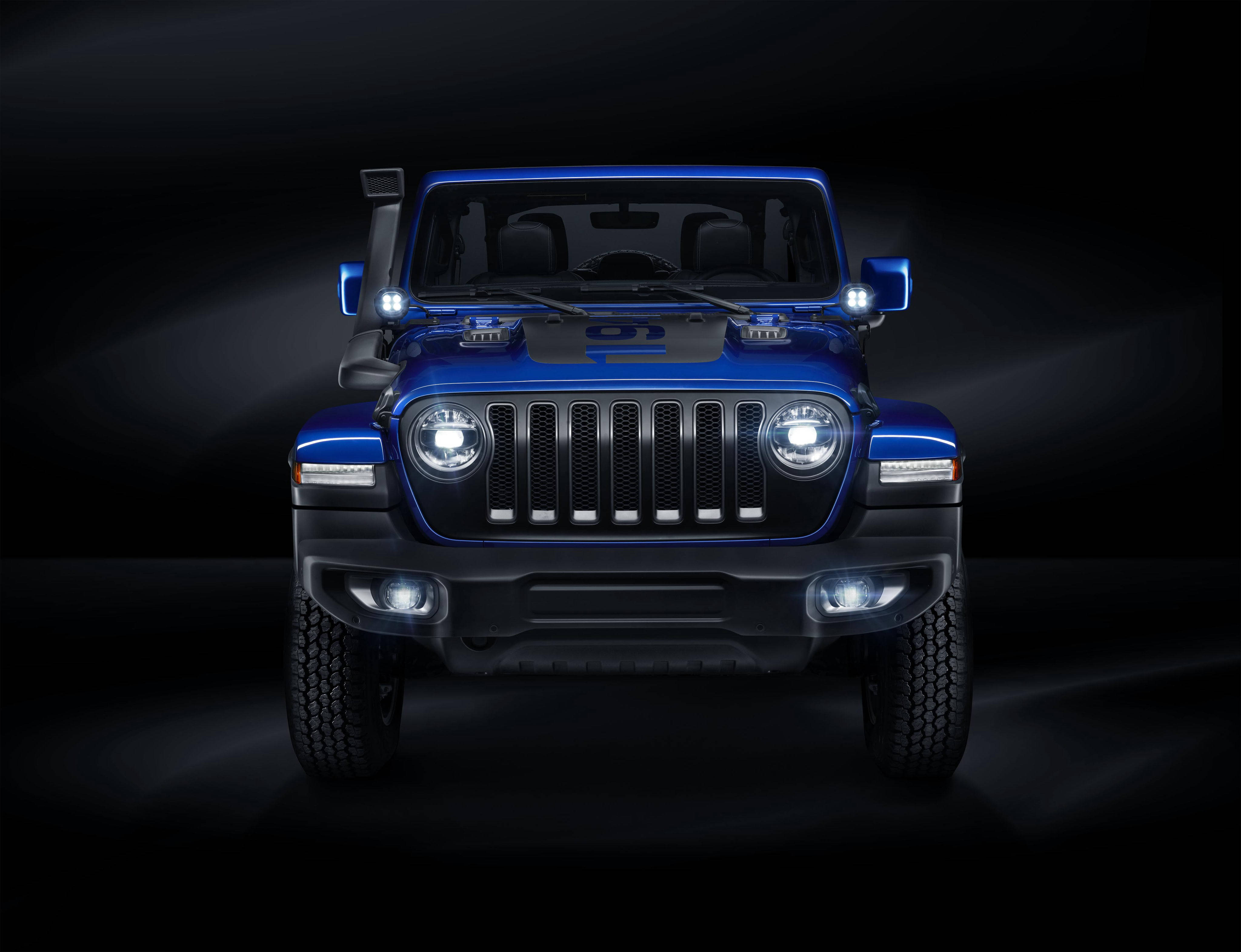 Mopar Jeep Wrangler Unlimited 壁紙 — 一輛引人注目的藍色Jeep Wrangler，車頭燈閃爍，在黑暗的攝影棚環境中佔據主導地位，散發出力量和粗獷的優雅。