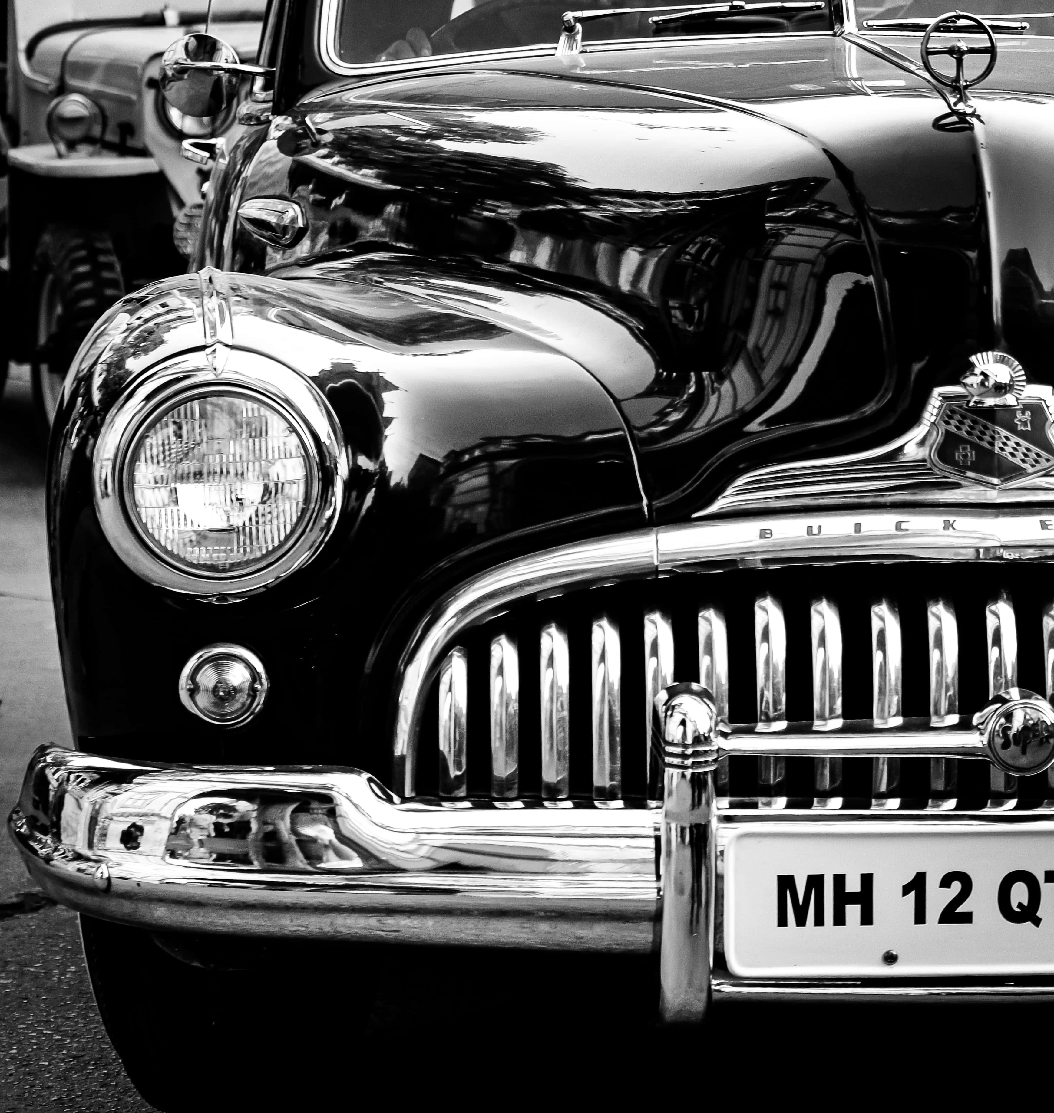 Black And White Vintage Car 桌布 壁紙 — 一輛復古別克汽車閃亮鍍鉻格柵和頭燈反射周圍環境的醒目黑白特寫。