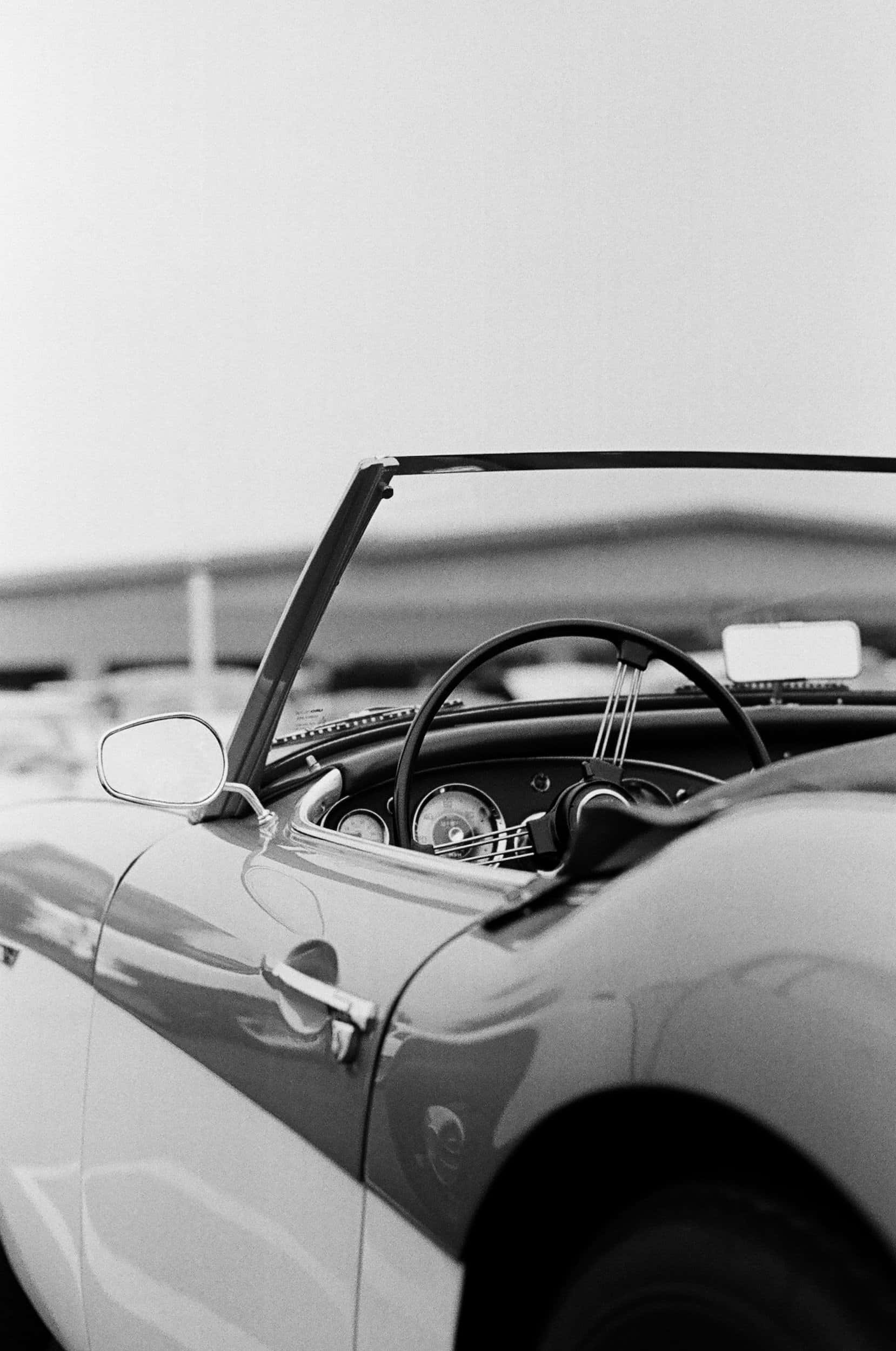 Black And White Vintage Car 桌布 壁紙 — 一輛復古敞篷車的流暢曲線和經典儀表板細節的黑白特寫。