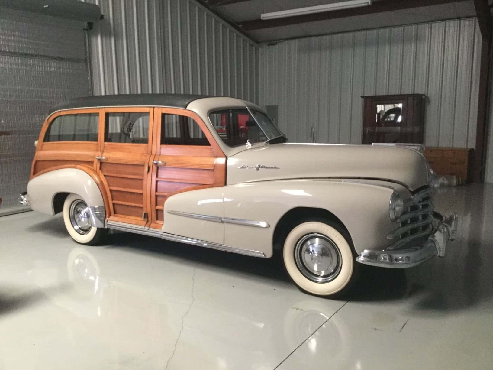 Pontiac Streamliner 桌布 壁紙 — 一輛復古木紋旅行車在乾淨的金屬牆車庫內，在明亮燈光下閃閃發光。