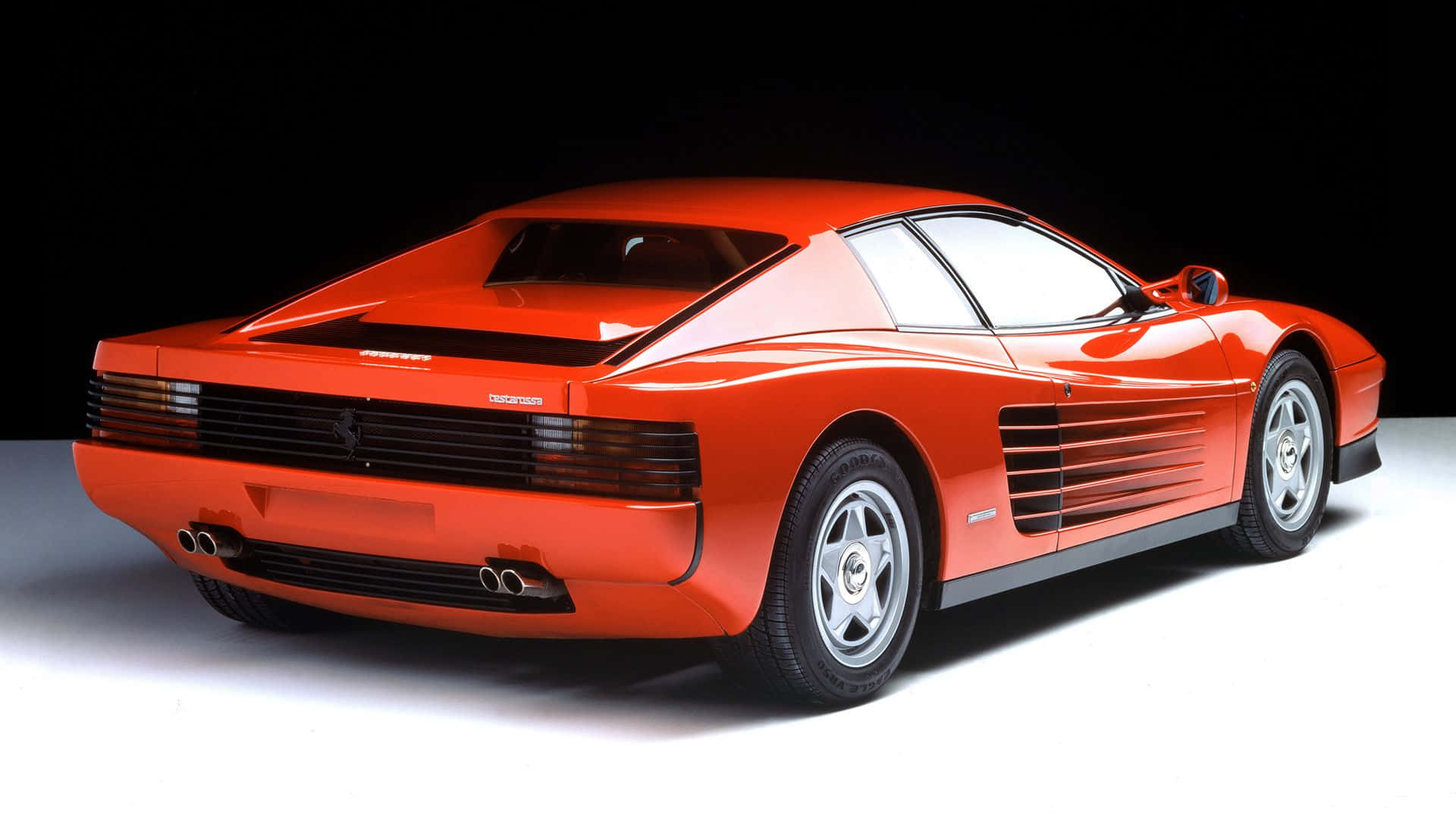 Ferrari Testarossa 桌布 壁紙 — 一輛搶眼的橙色法拉利 Testarossa 在攝影棚燈光下，以鮮明的黑白背景襯托，閃閃發光。