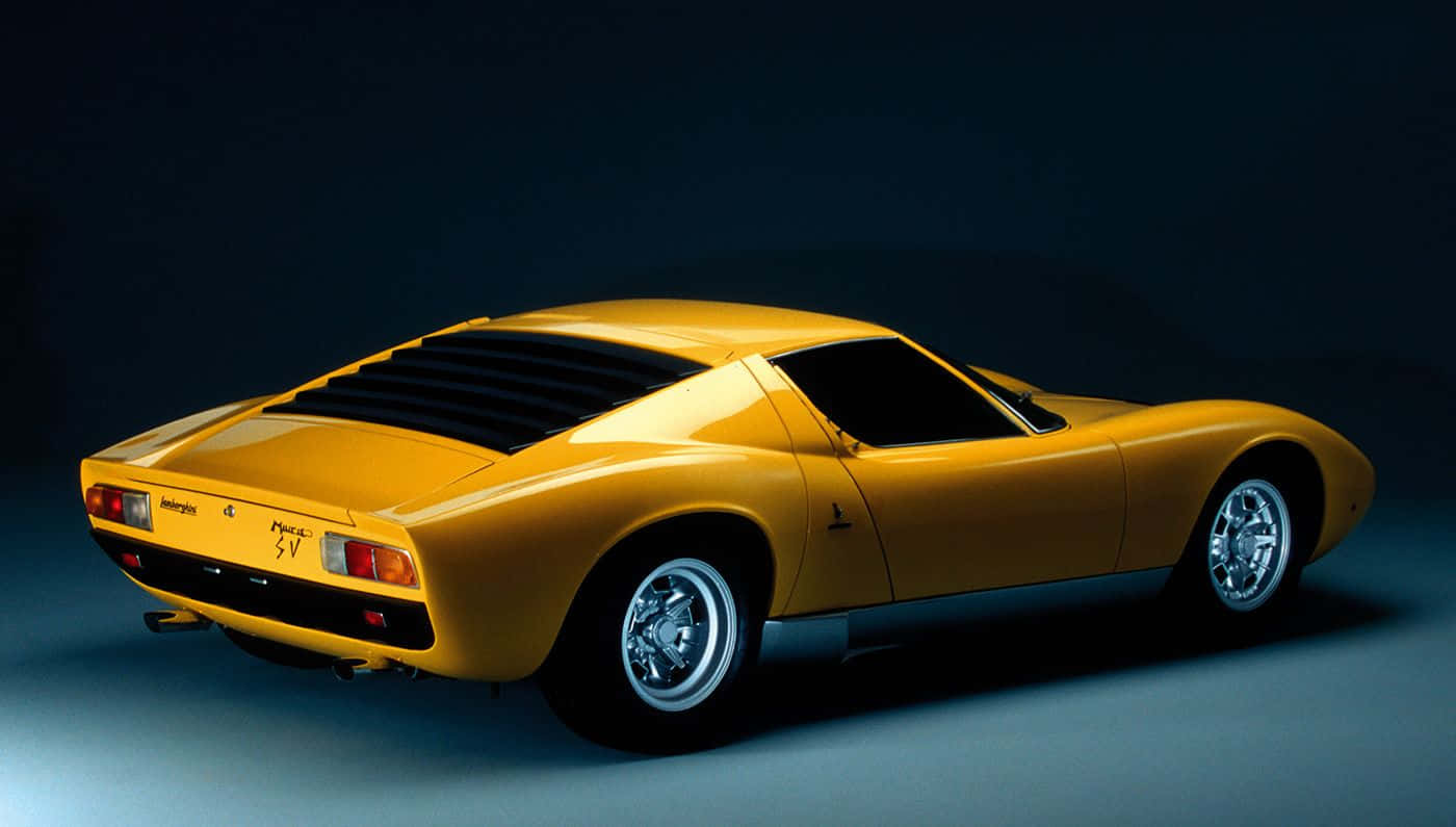 Lamborghini Miura 桌布 壁紙 — 一輛搶眼的黃色林寶堅尼 Miura SV 跑車在深色背景的攝影棚燈光下閃耀。