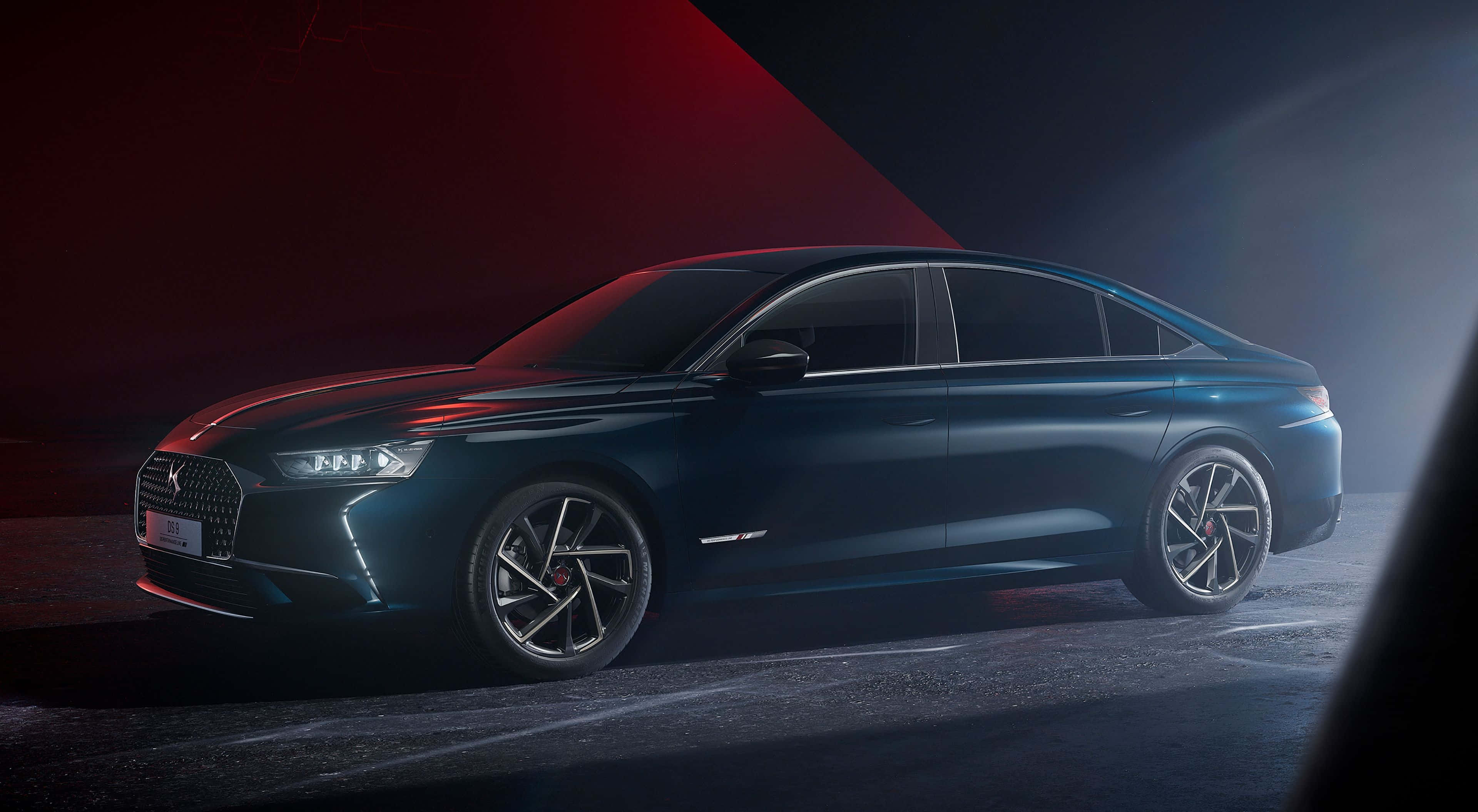 Ds Automobiles 桌布 壁紙 — 一輛時尚深藍色轎車在戲劇性的紅藍攝影棚燈光及煙霧效果下閃閃發光。