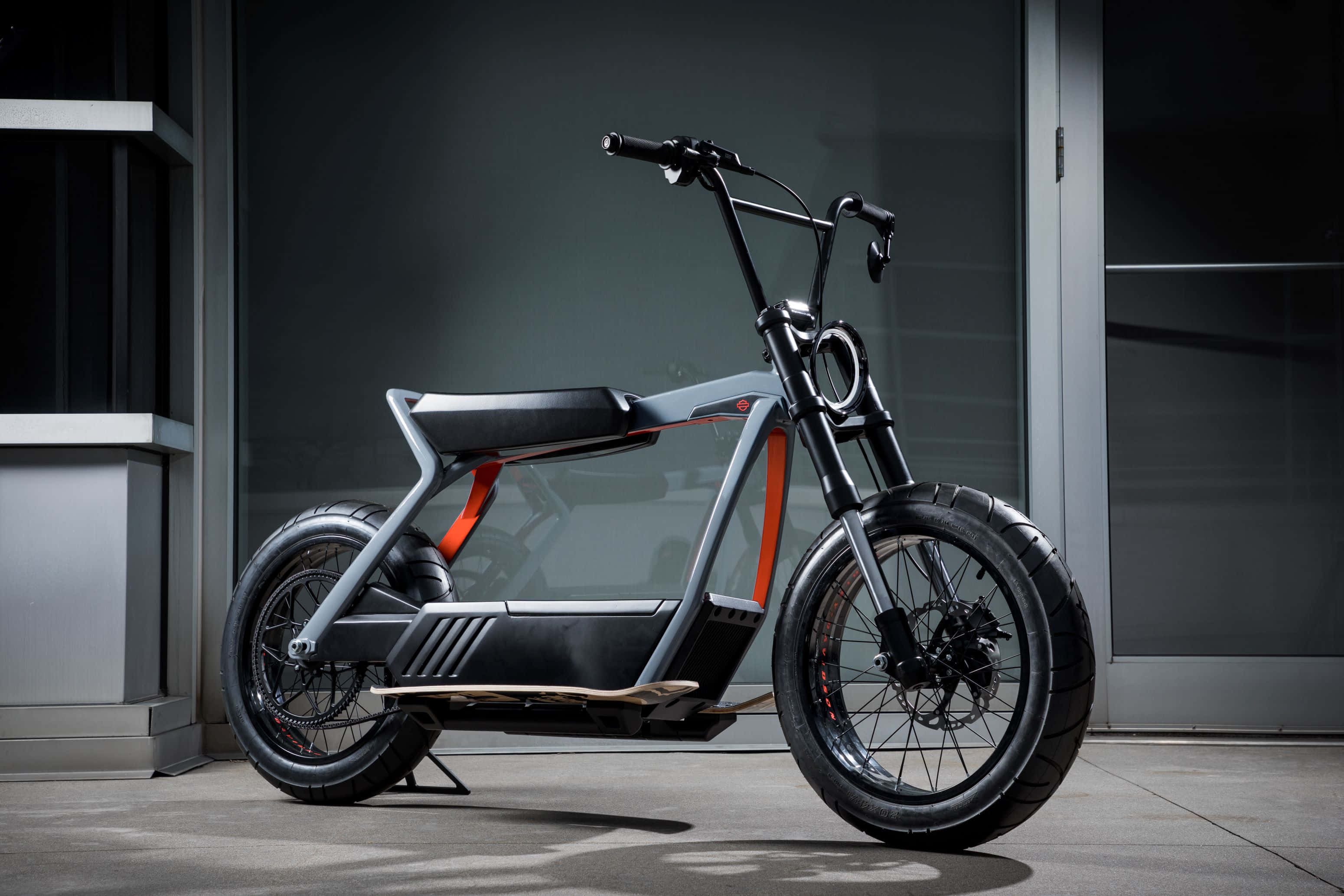 Electric Bike 桌布 壁紙 — 一輛時尚現代電動單車帶有醒目橙色點綴，停放在極簡城市建築外牆前。