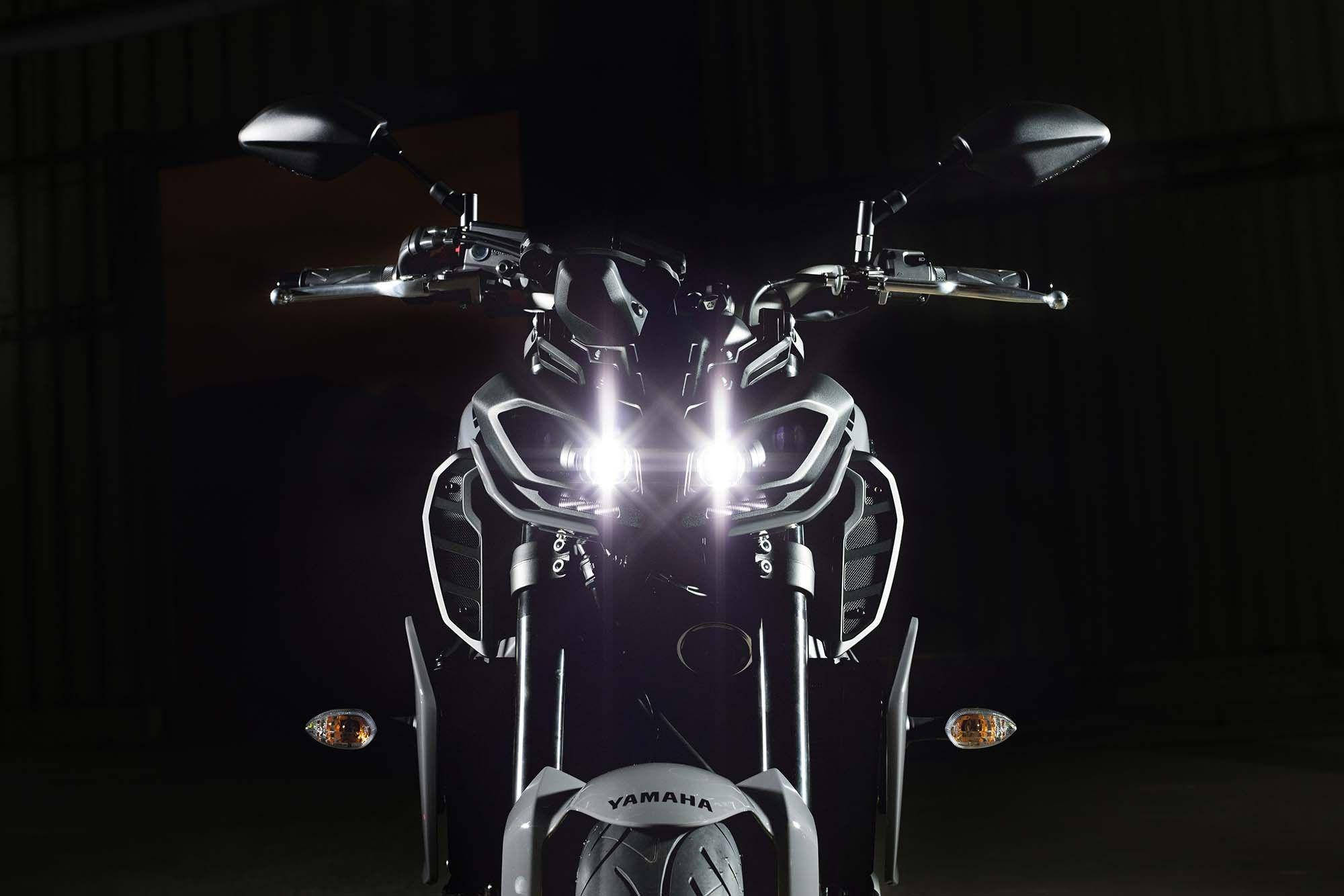 yamaha mt 15 桌布 壁紙 — 一輛時尚的Yamaha電單車的發光頭燈在戲劇性的攝影棚拍攝中刺穿黑暗。