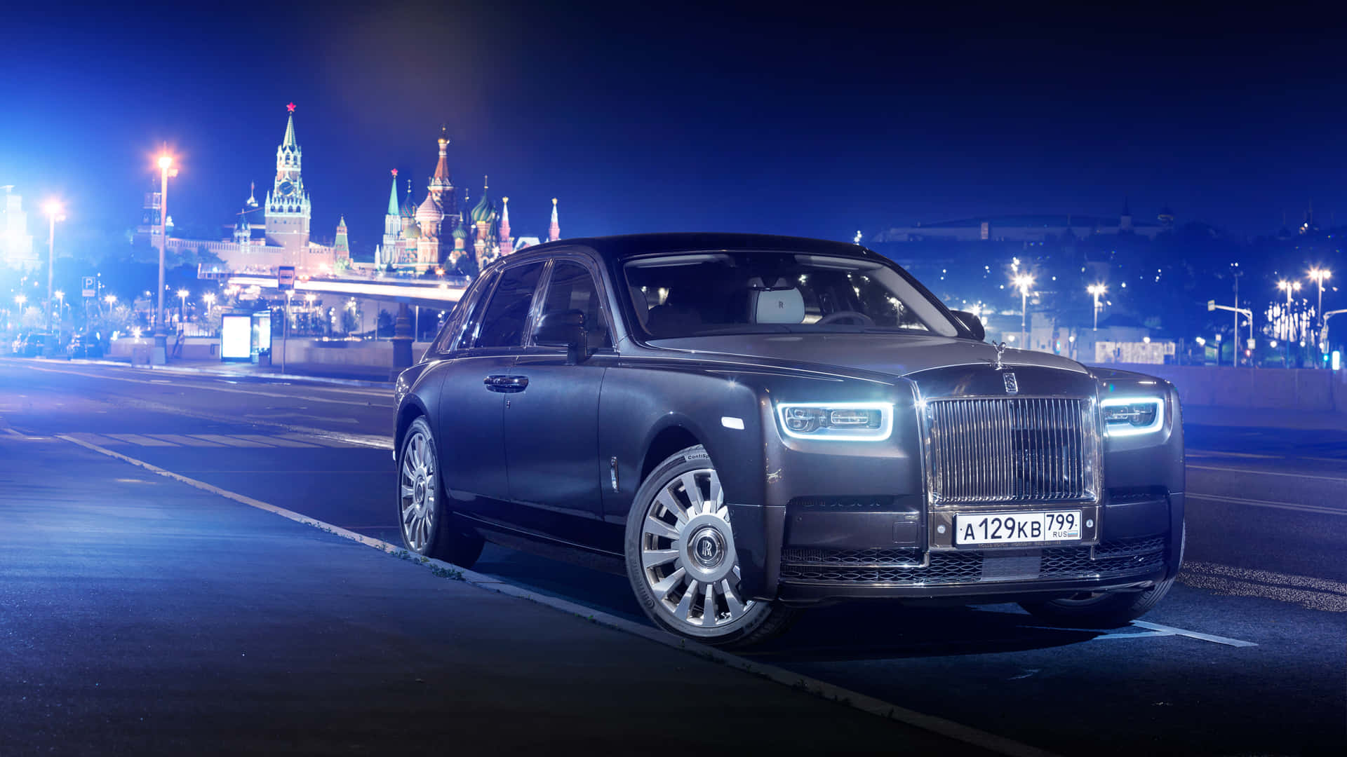 Rolls Royce 桌布 壁紙 — 一輛時尚的啞光黑色勞斯萊斯 Ghost 在夜間滑行經過燈火通明的克里姆林宮和莫斯科聖瓦西里主教座堂。