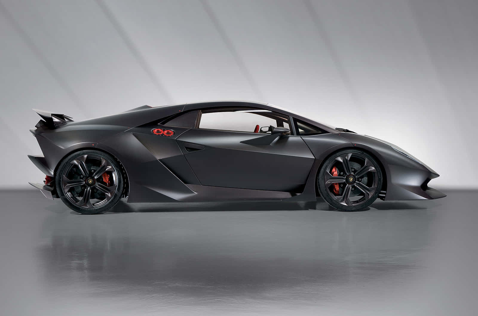Lamborghini Sesto Elemento 桌布 壁紙 — 一輛時尚的啞光黑色林寶堅尼跑車，帶有紅色點綴和空氣動力學設計，在簡約的工作室中擺拍。