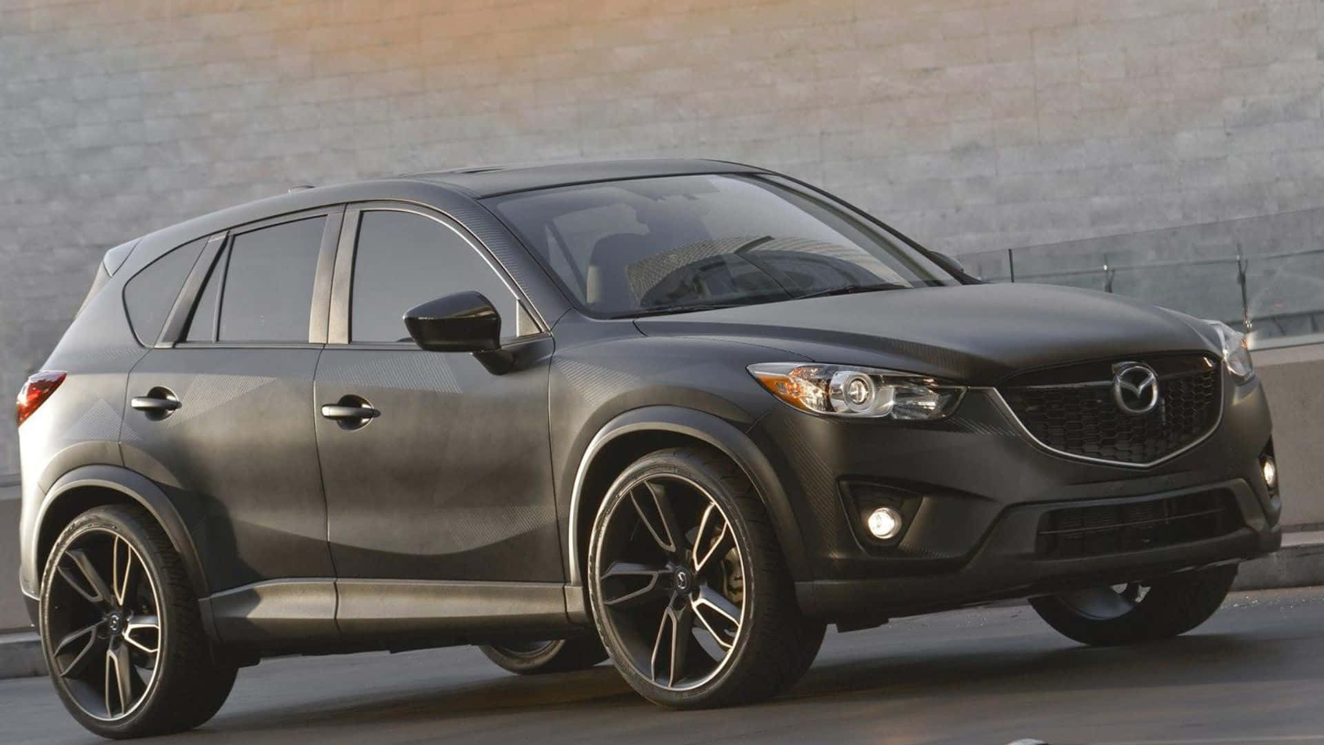Mazda Cx-5 桌布 壁紙 — 一輛時尚的啞光黑色萬事得CX-5 SUV停靠在混凝土牆邊，配備時尚合金輪圈。