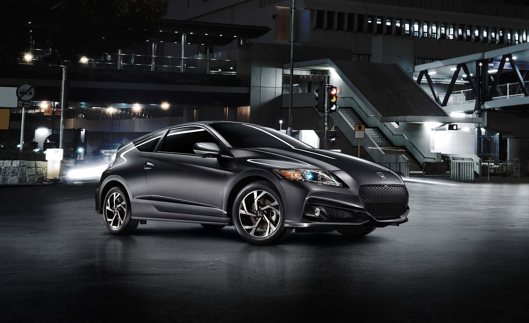 Honda Cr-z 桌布 壁紙 — 一輛時尚的啞光黑色跑車在夜間城市環境中，在潮濕路面的倒影下閃爍著城市燈光。