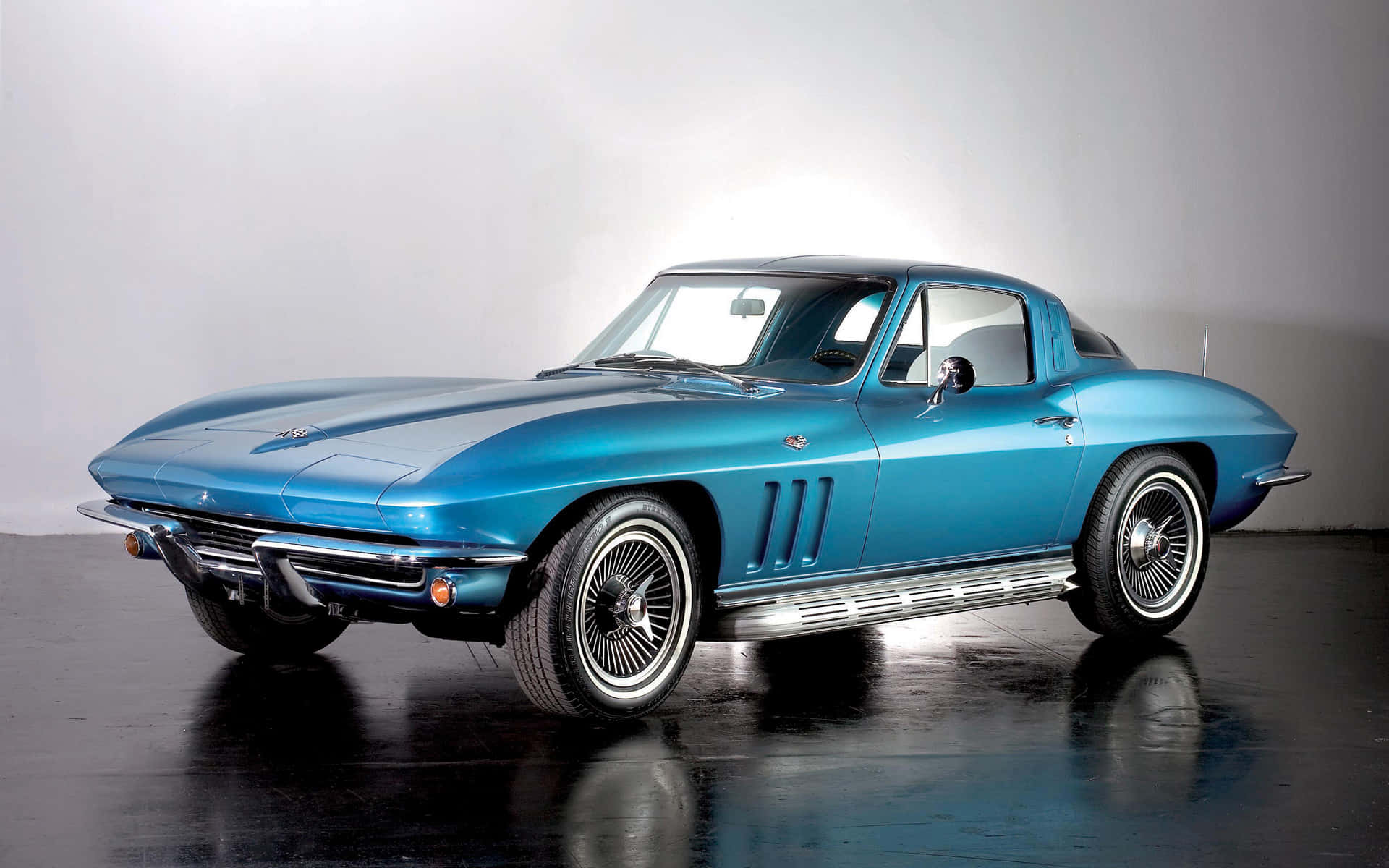 classic 桌布 壁紙 — 一輛時尚的復古藍色Corvette跑車在攝影棚燈光下，於反光的黑色地板上閃閃發光。