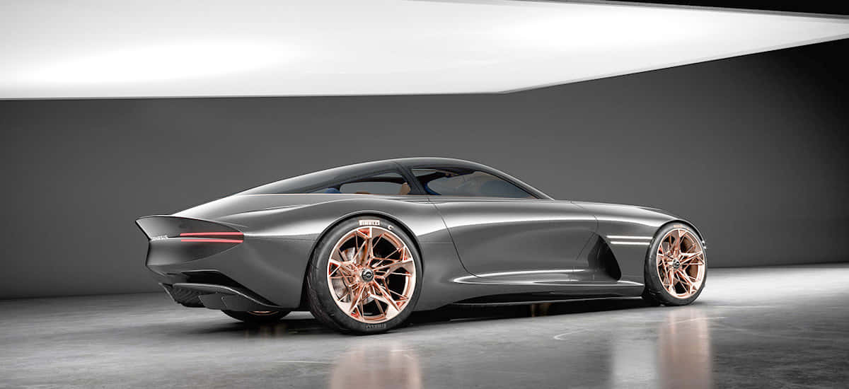 Genesis Essentia 桌布 壁紙 — 一輛時尚的未來主義跑車，配備玫瑰金輪圈和啞光灰色車身，在攝影棚燈光下閃耀。