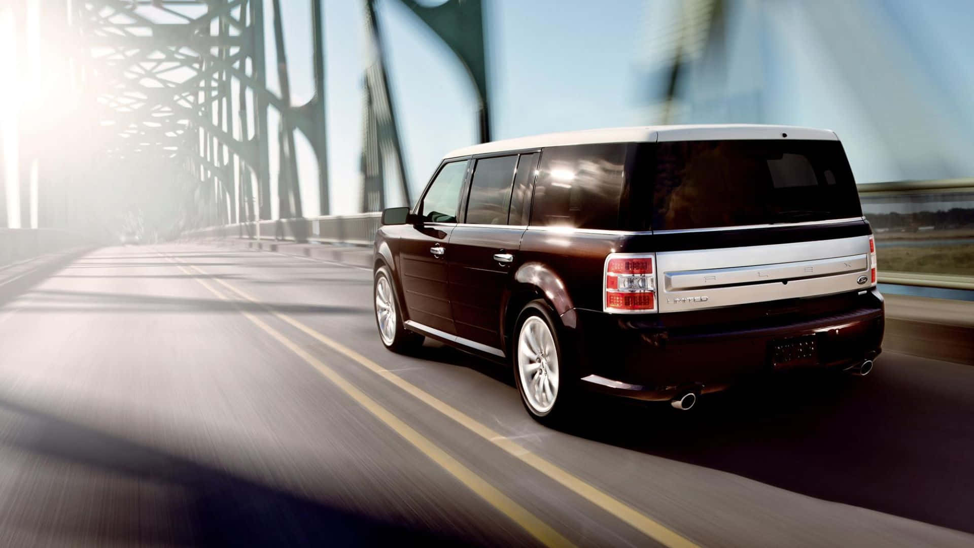 Ford Flex 桌布 壁紙 — 一輛時尚的棗紅色SUV在鋼橋上行駛，動態模糊效果強調了明亮日光下的速度感。