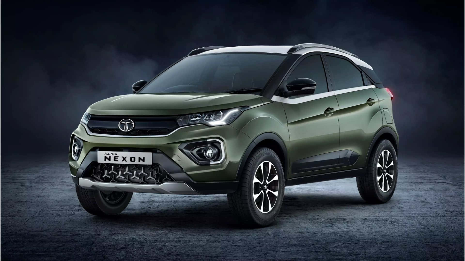 Tata Motors 桌布 壁紙 — 一輛時尚的橄欖綠色 Tata Nexon SUV 在昏暗、氣氛十足的攝影棚背景下，搭配戲劇性的燈光，靜止不動。