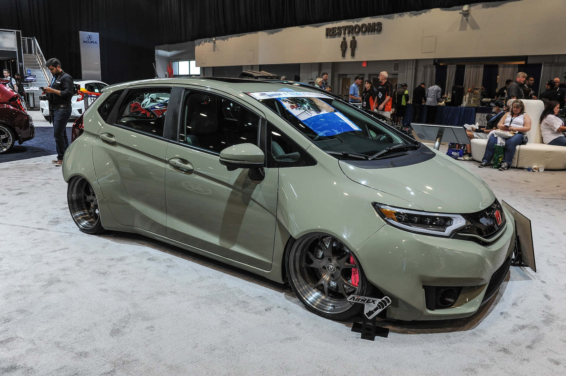 Honda Fit 桌布 壁紙 — 一輛時尚的橄欖綠色改裝本田Fit在車展上展出，配備閃亮的定制輪圈和降低的車身姿態。