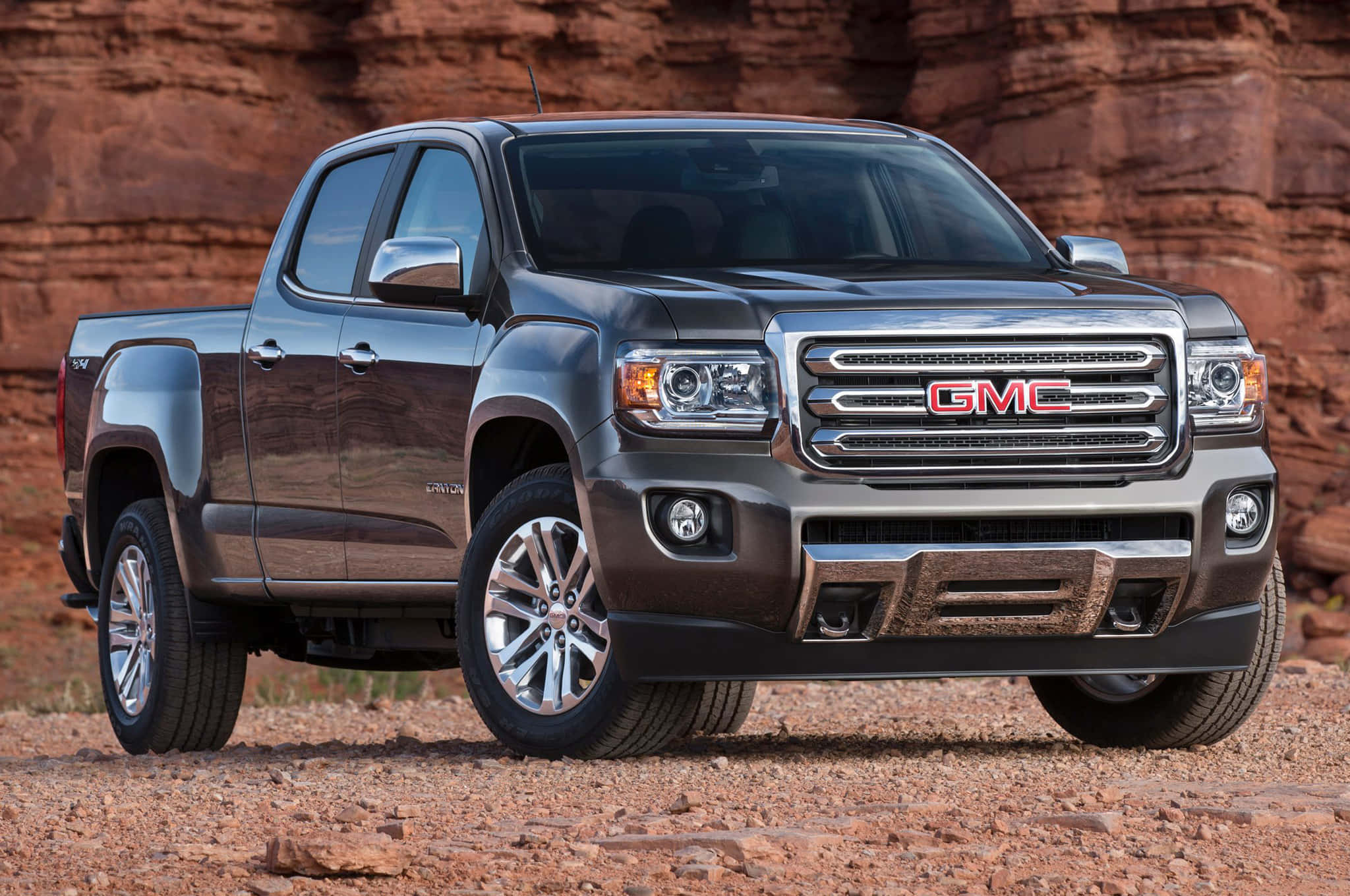Gmc Canyon 桌布 壁紙 — 一輛時尚的深灰色 GMC Canyon 皮卡車停在紅色岩石地形上，背景是崎嶇的峽谷。