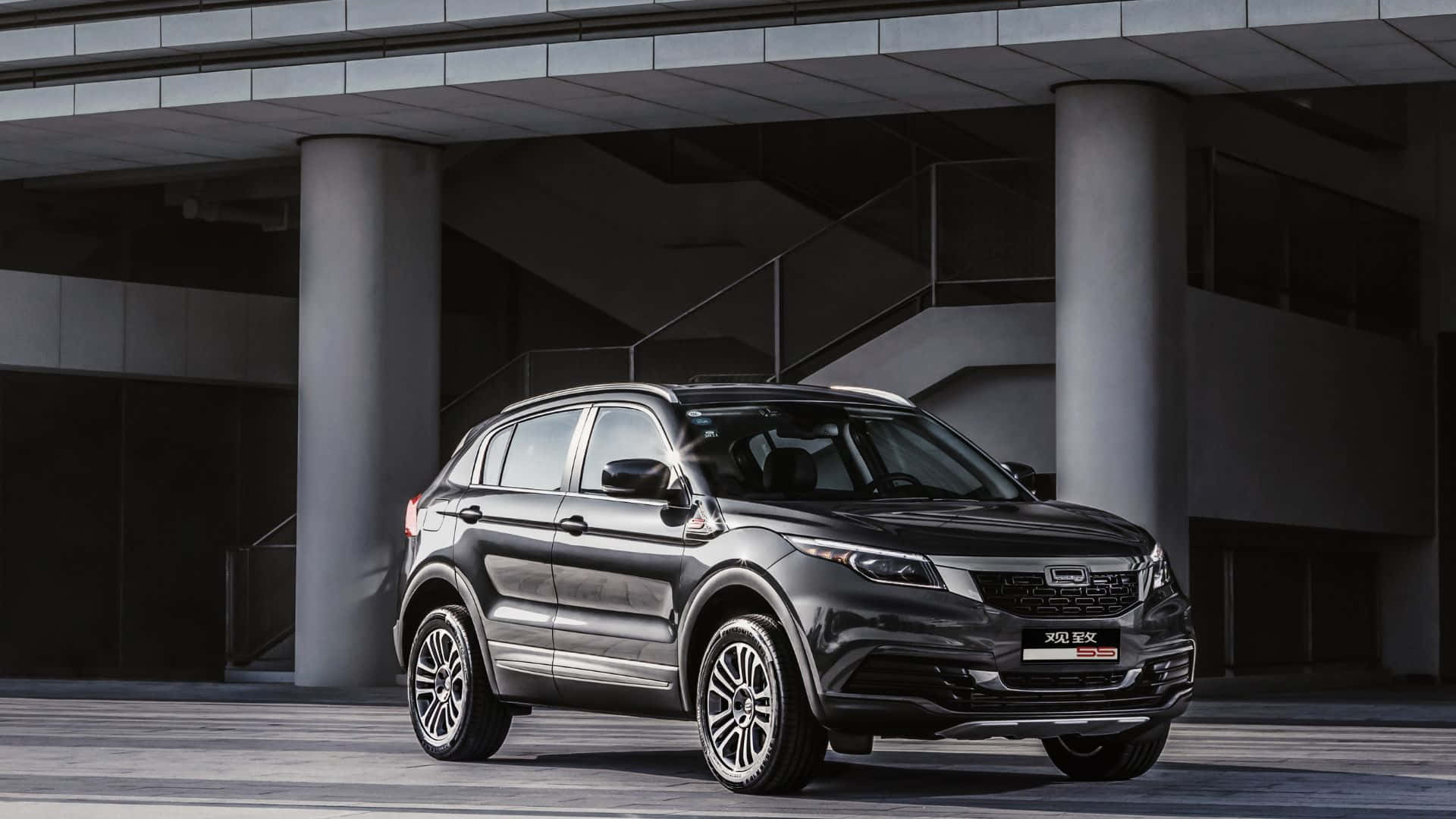 Qoros 桌布 壁紙 — 一輛時尚的深灰色SUV停放在現代混凝土高架橋下，具有工業建築風格。