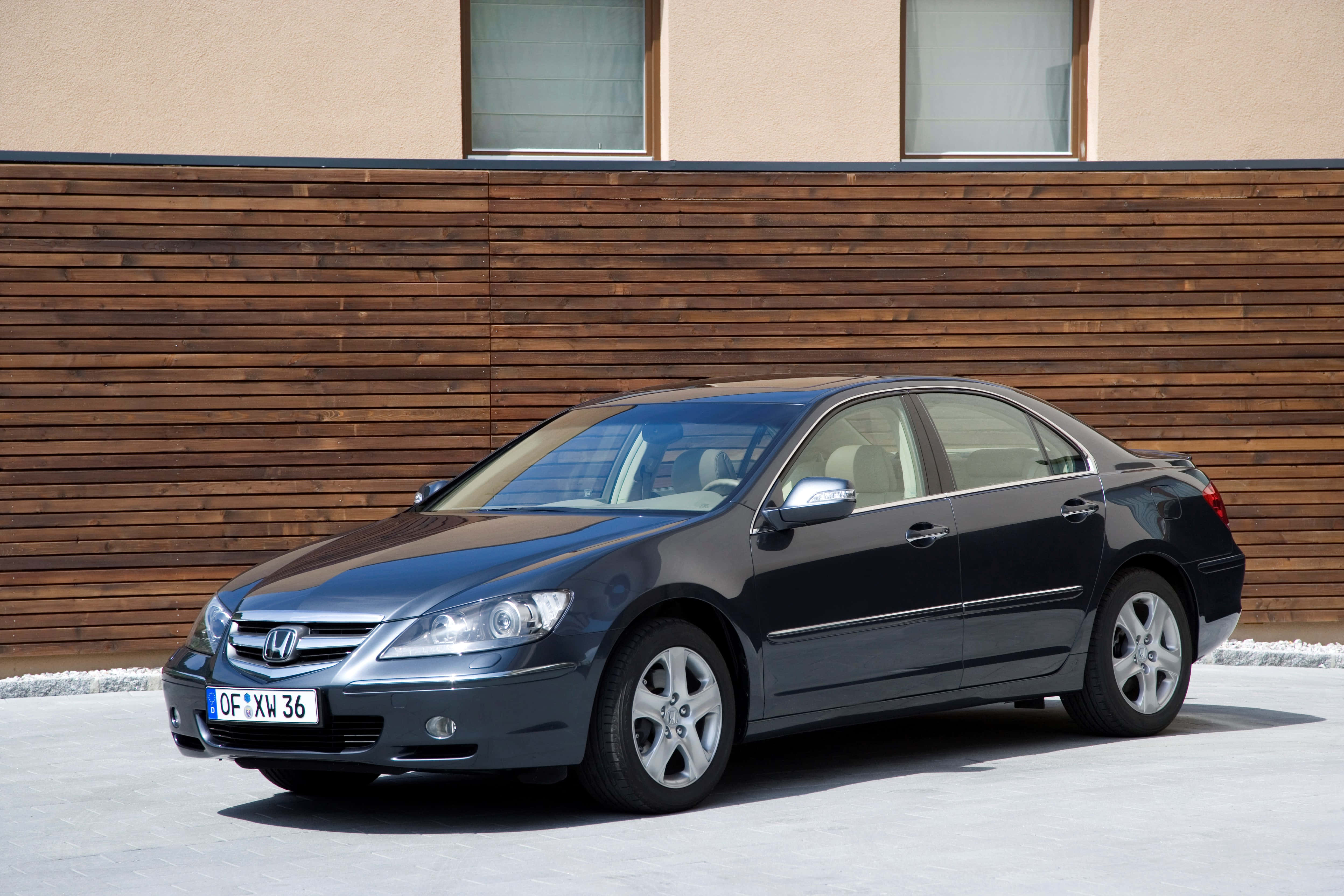 Honda Legend 桌布 壁紙 — 一輛時尚的深灰色本田雅閣轎車在明亮的日光下停放在現代木牆前。