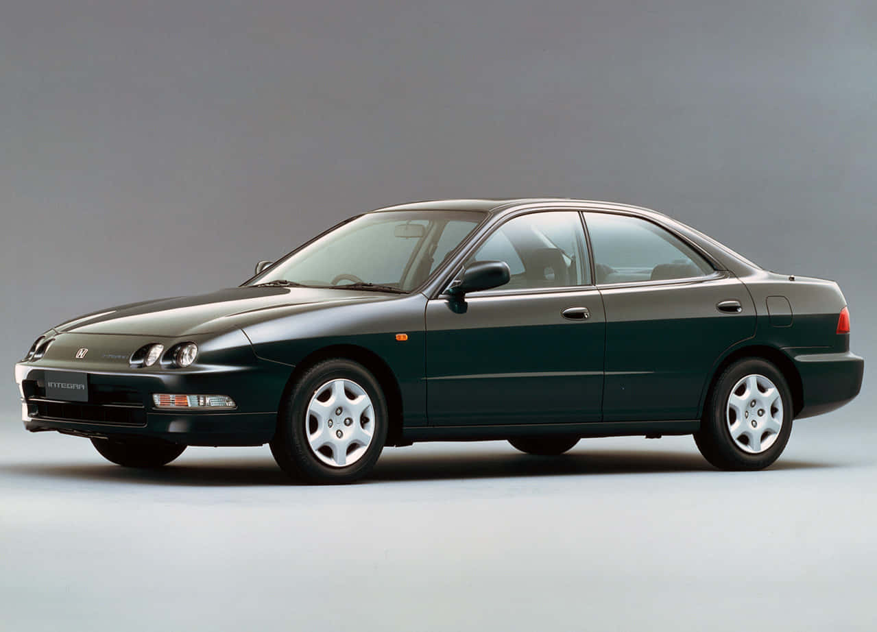Honda Integra 桌布 壁紙 — 一輛時尚的深綠色1990年代本田Prelude轎車，側面展示在灰色中性工作室背景前。