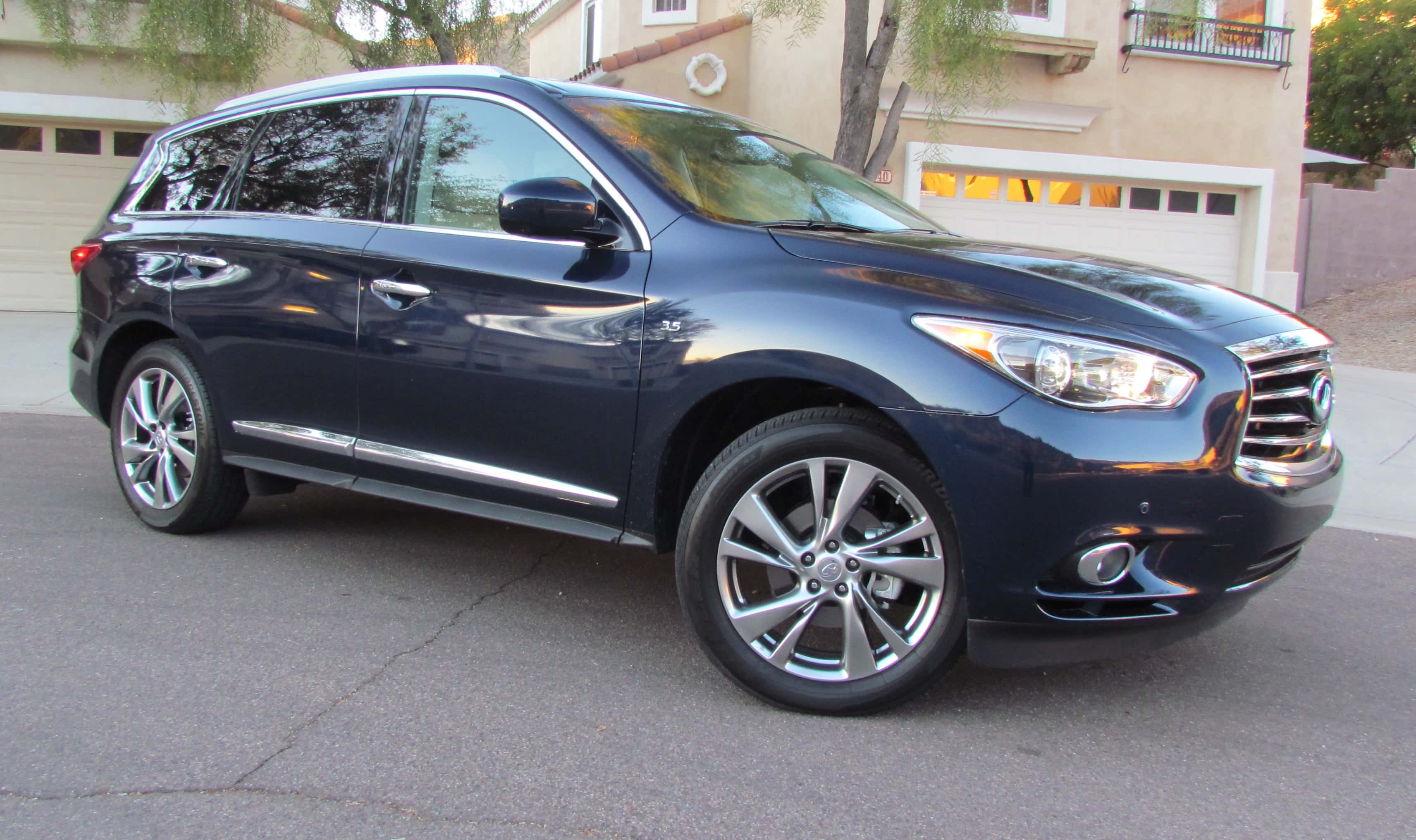 Infiniti Qx60 桌布 壁紙 — 一輛時尚的深藍色 Infiniti QX60 SUV 停放在住宅街道上，溫暖的傍晚光線反射在其拋光的表面上。