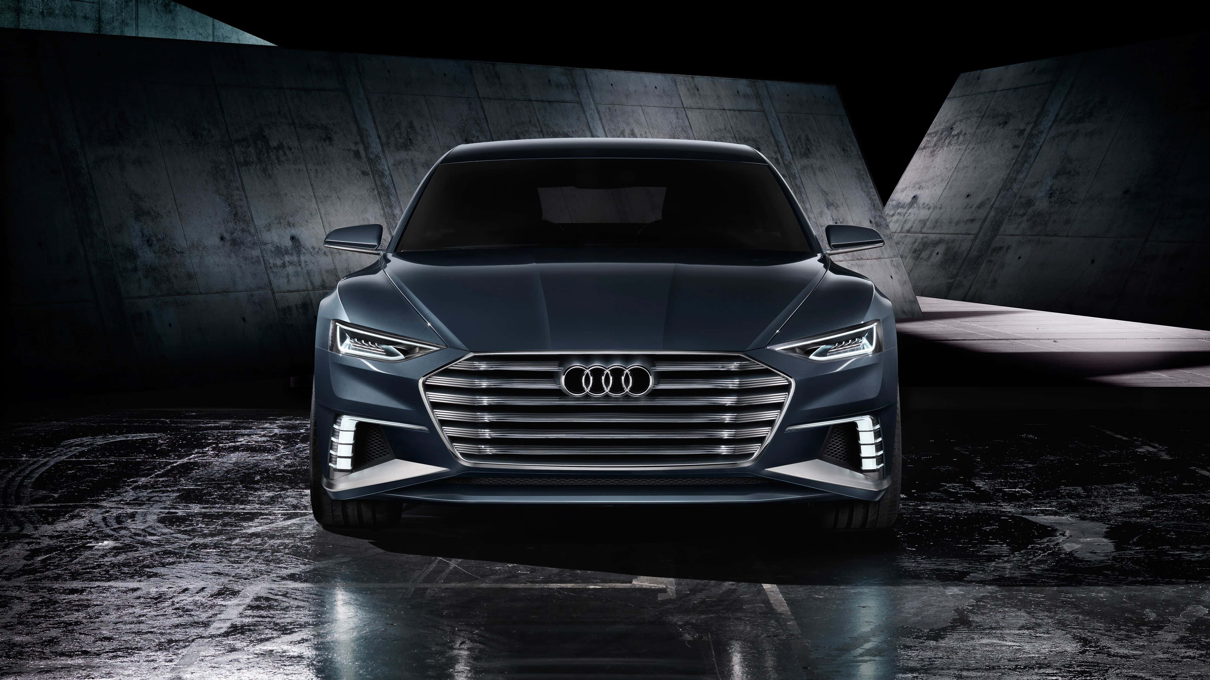 Audi S8 桌布 壁紙 — 一輛時尚的深藍色奧迪概念車，配備發光車頭燈，位於光線昏暗的混凝土隧道中央，地面濕滑反光。