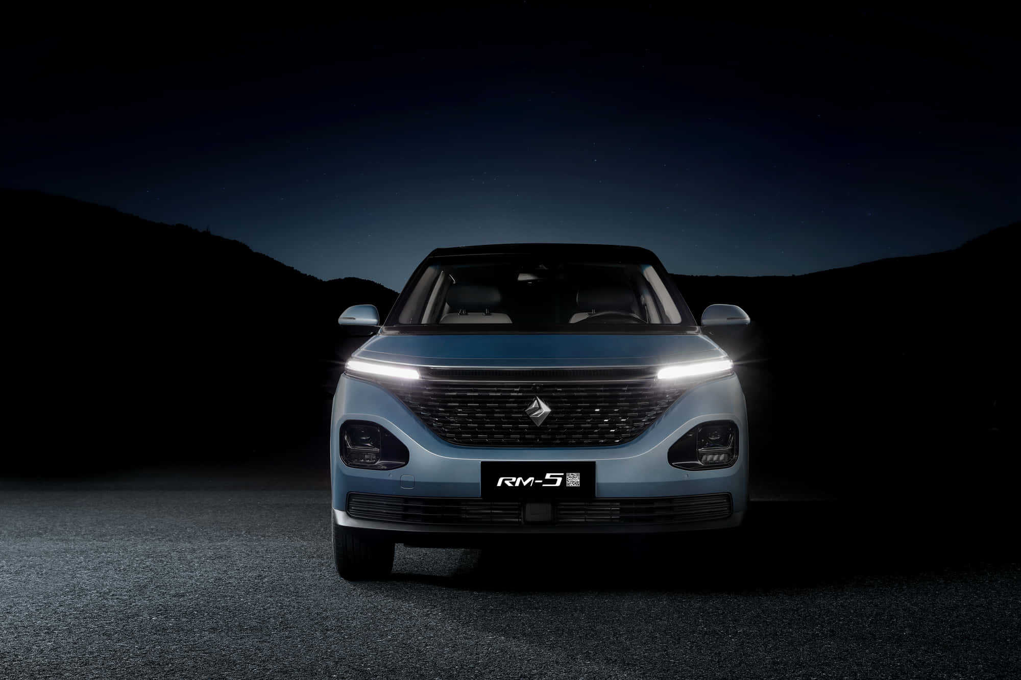 Baojun 桌布 壁紙 — 一輛時尚的淺藍色SUV，帶有發光的車頭燈，在星空下、有輪廓山丘的黑暗道路中央。