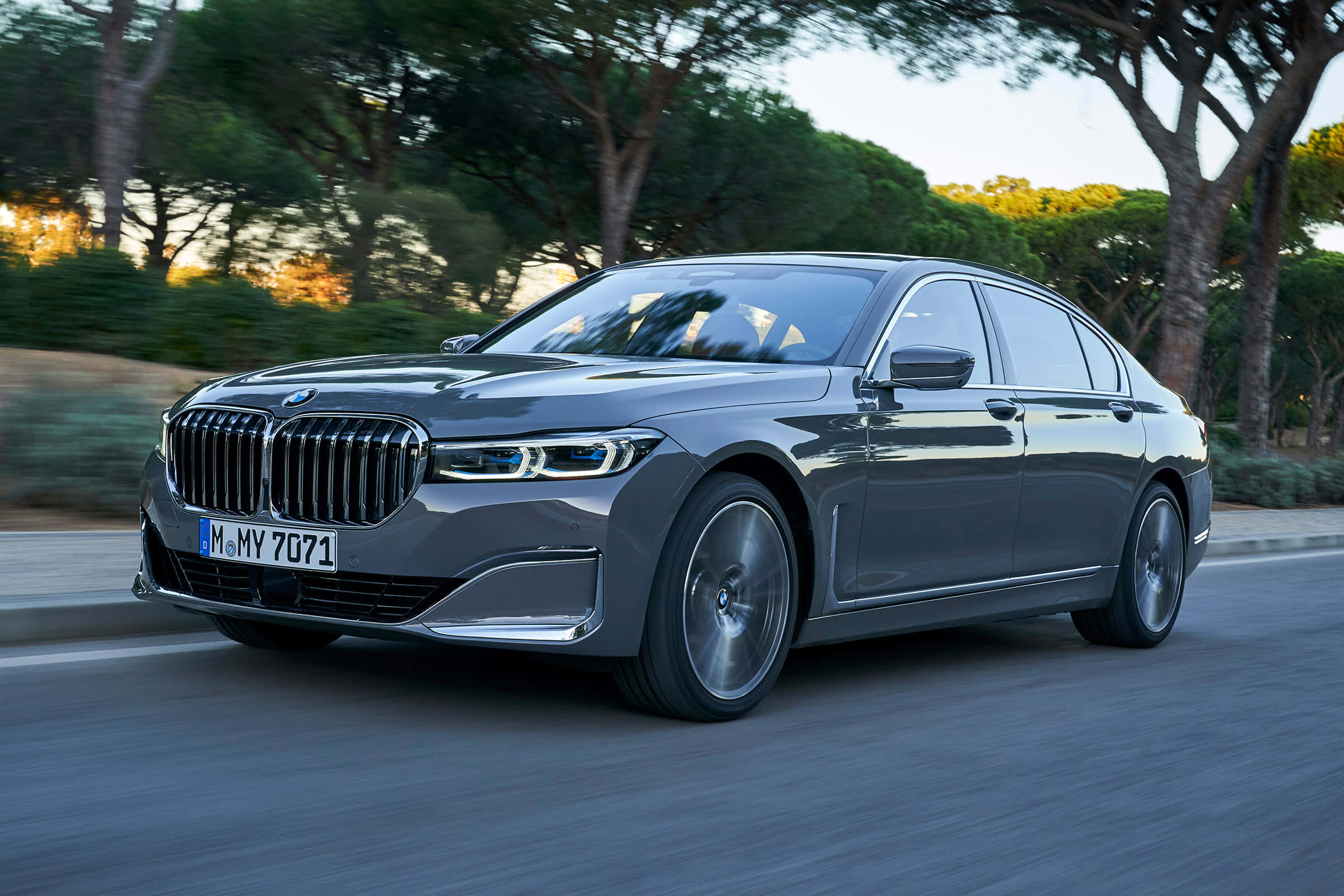 Bmw 7 Series 桌布 壁紙 — 一輛時尚的灰色BMW 7系轎車在黃金時段沿著綠樹成蔭的道路疾馳，動態模糊傳達出動感。