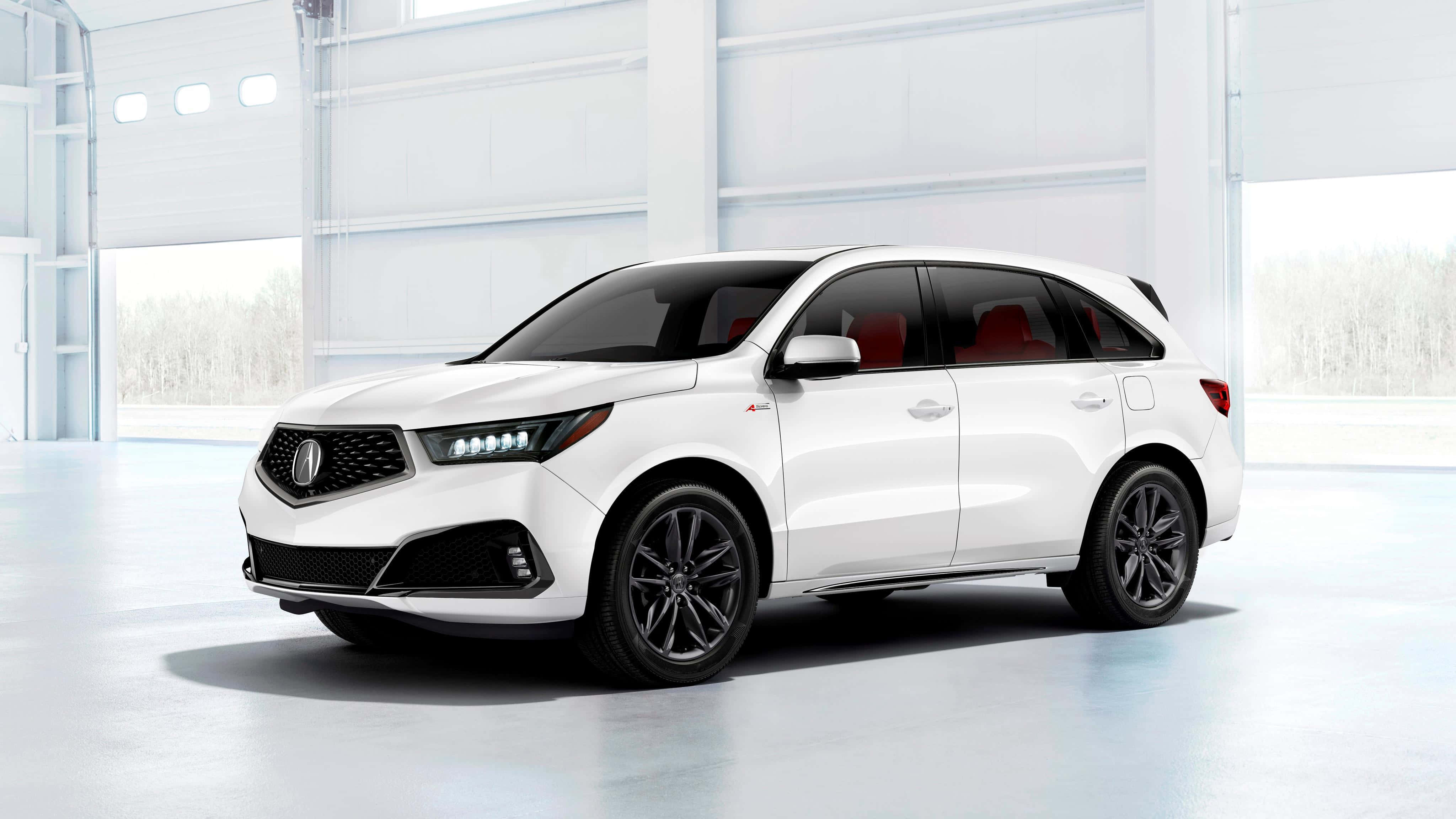 Acura Mdx 桌布 壁紙 — 一輛時尚的白色Acura SUV，配備黑色輪圈和紅色內飾，停放在明亮簡約的車庫中，外面可見積雪的樹木。