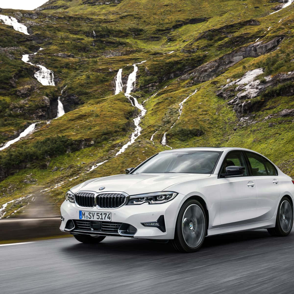Bmw 3 Series 桌布 壁紙 — 一輛時尚的白色BMW轎車沿著山路疾馳，背景是層疊的瀑布和鬱鬱蔥蔥的綠色山坡。