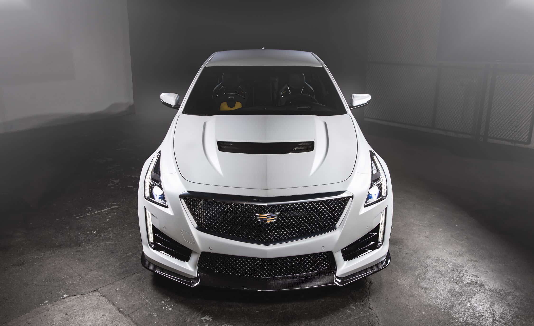 Cadillac Cts 桌布 壁紙 — 一輛時尚的白色Cadillac ATS-V跑車，具有侵略性造型和發光頭燈，位於煙霧瀰漫、燈光昏暗的車庫中央。