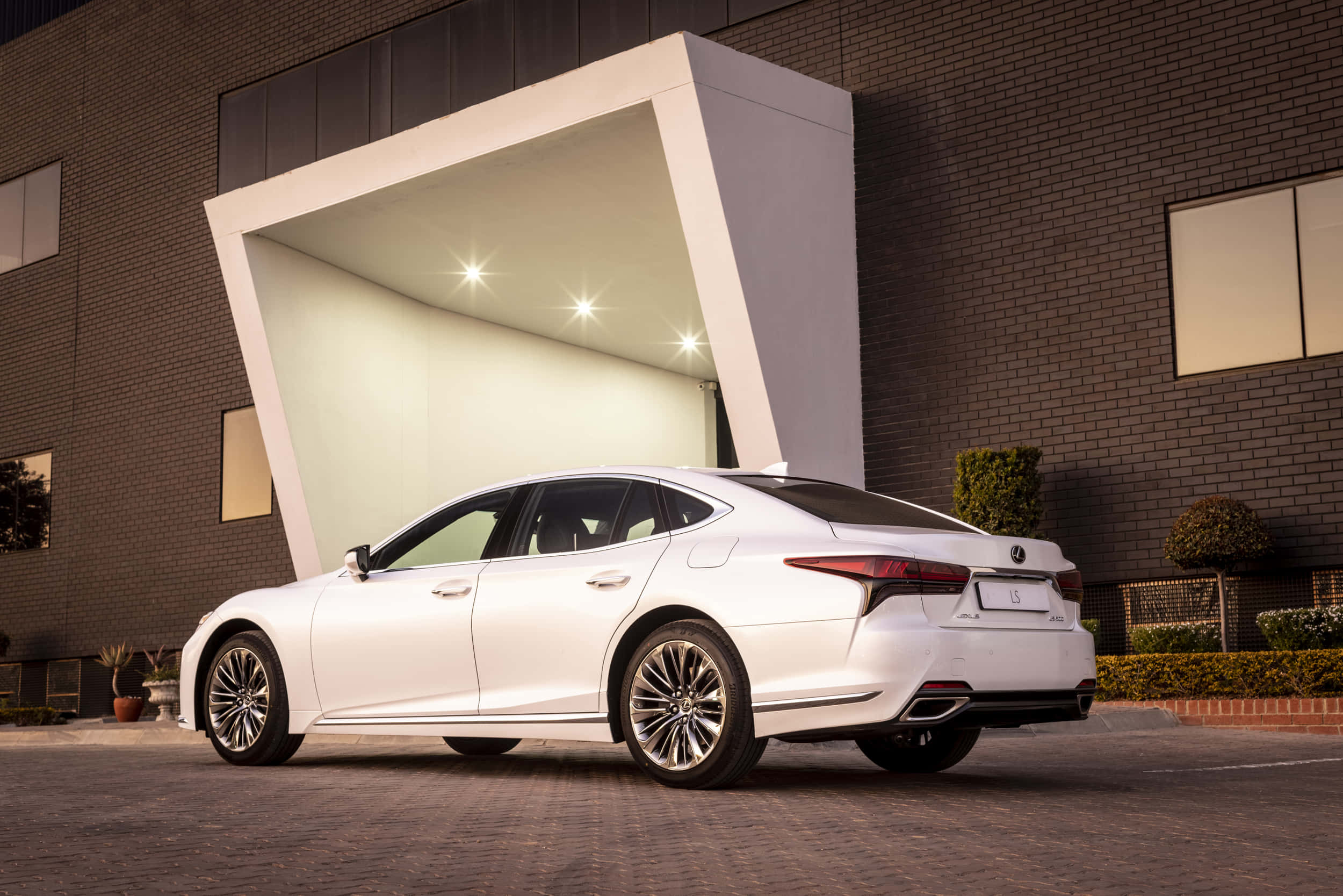 Lexus Ls 500 桌布 壁紙 — 一輛時尚的白色Lexus LS轎車在黃昏時停放在現代白色建築簷篷下。