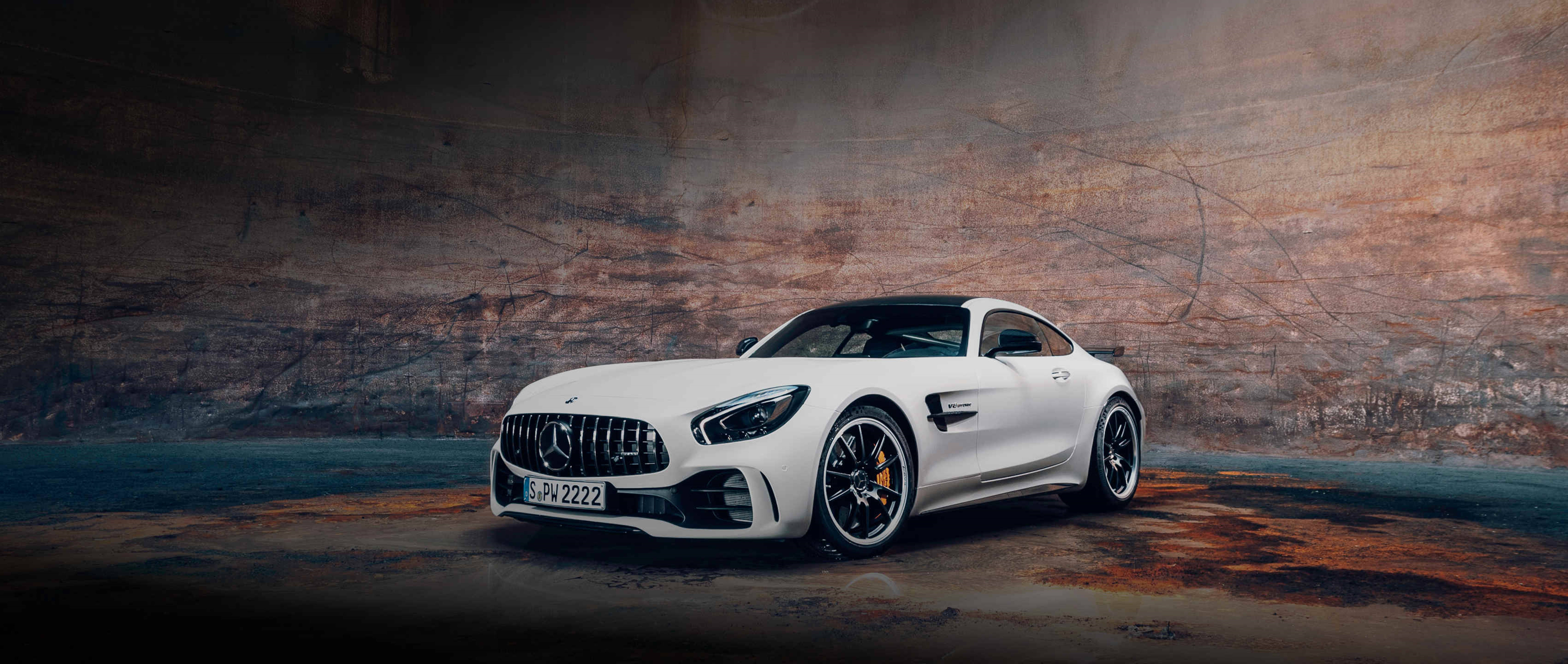 HD mercedes 桌布 壁紙 — 一輛時尚的白色Mercedes-AMG GT停在粗獷的工業隧道中，帶有戲劇性的燈光。