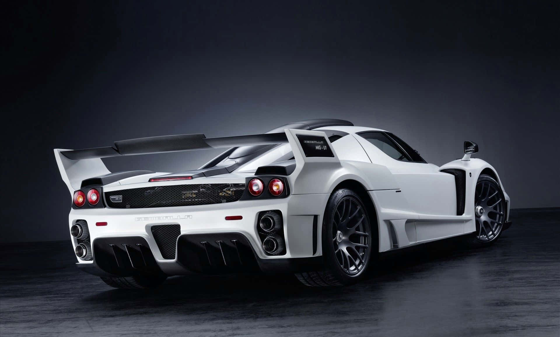 Ferrari Enzo 桌布 壁紙 — 一輛時尚的白色Pagani Zonda跑車，配備大型後擾流板和發光的紅色尾燈，在黑暗的攝影棚中展示。