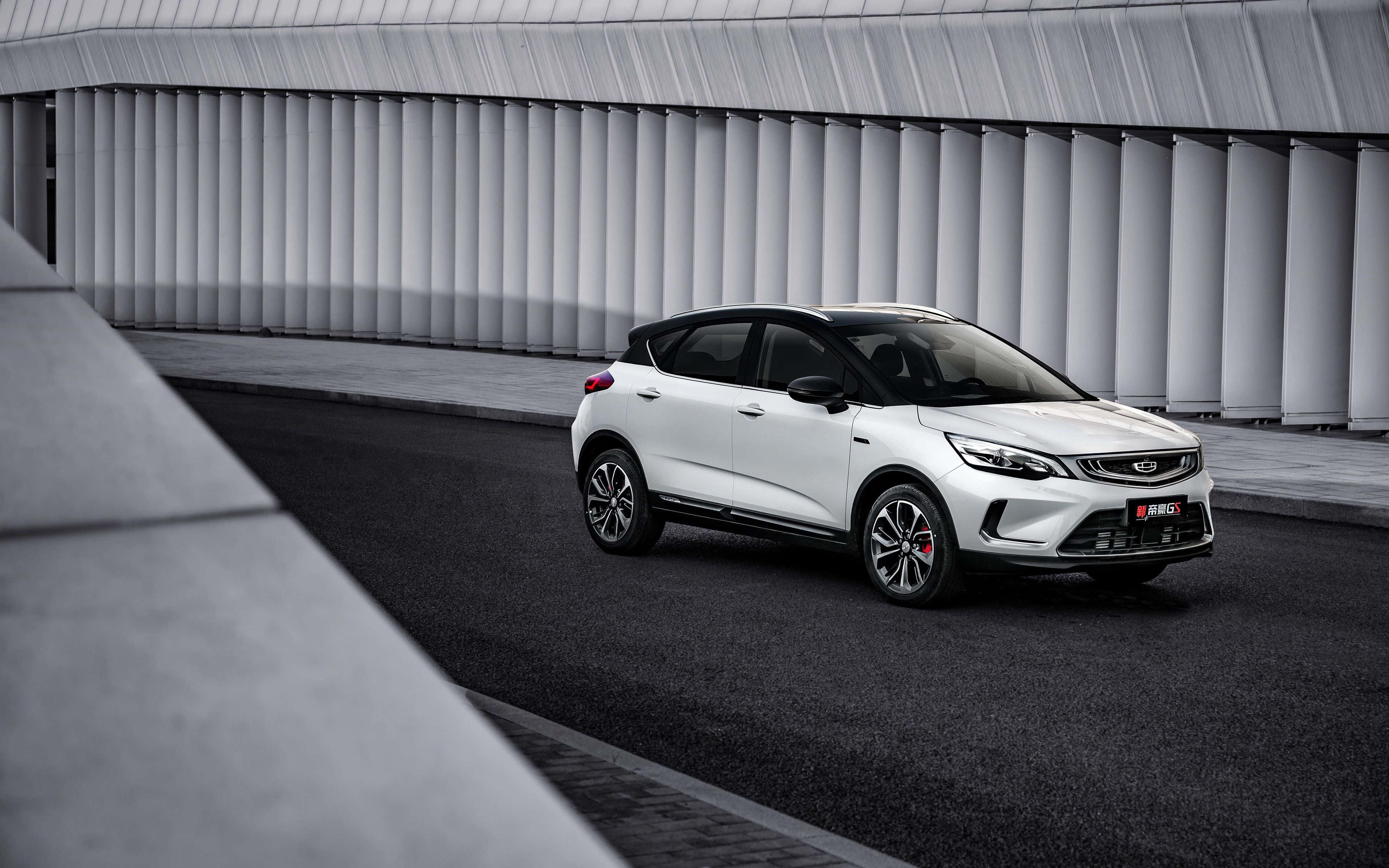 Geely 桌布 壁紙 — 一輛時尚的白色SUV停泊在黑暗的瀝青路上，下方是現代化的波紋金屬天橋，帶有幾何混凝土結構。
