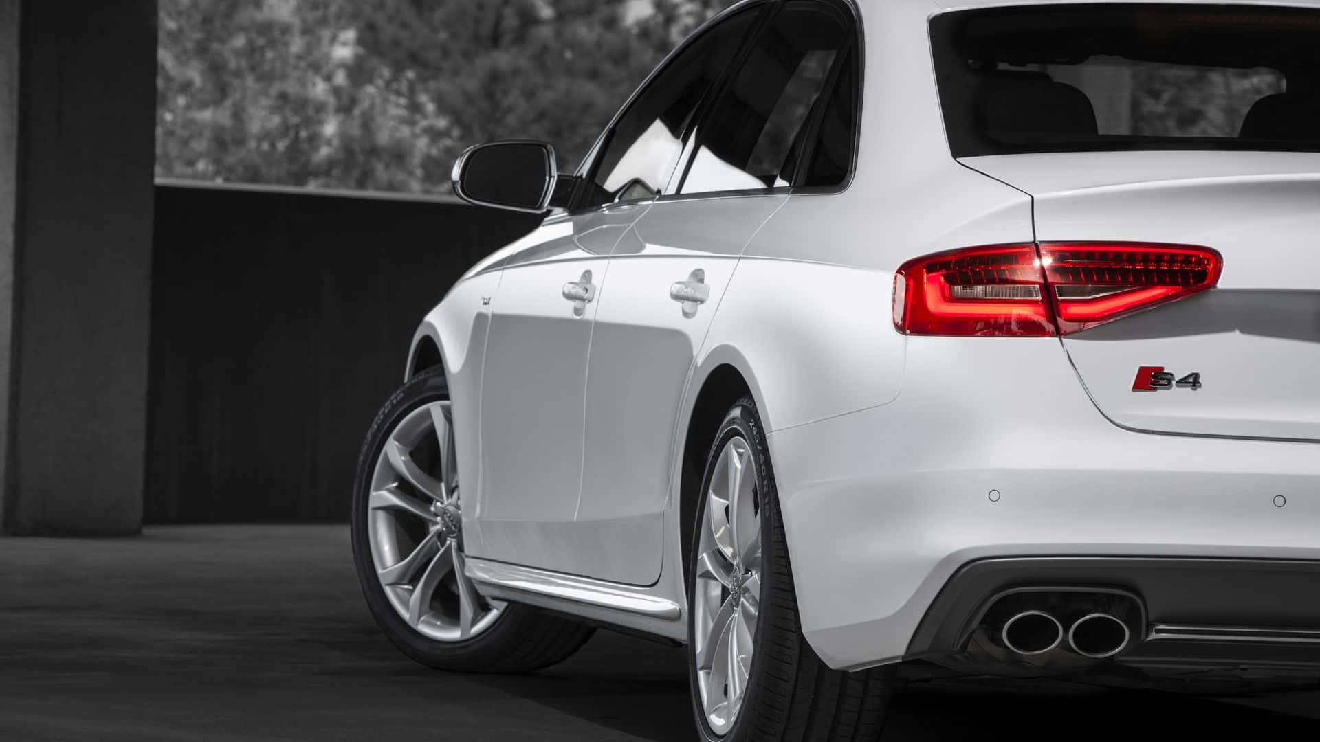 Audi S4 桌布 壁紙 — 一輛時尚的白色奧迪S4旅行車以後方四分之三視角展示，配備紅色尾燈和雙排氣管，背景為單色城市景觀。